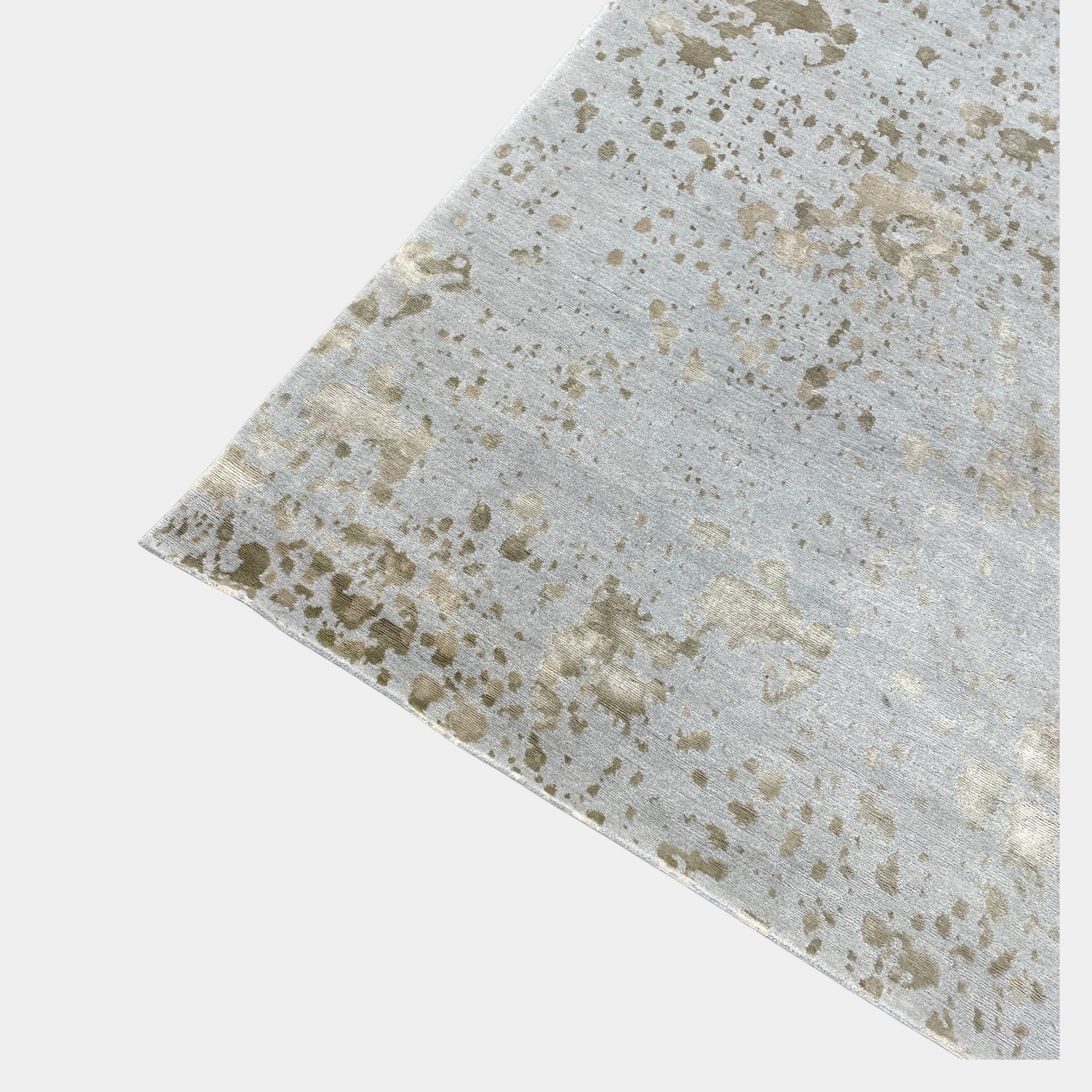 A section of the Delinear's 8 x 10 Delinier Splatter Rug features an abstract design with beige and gray spots, enhanced by Swiss Chromium Dye on Himalayan wool for vibrant detail.