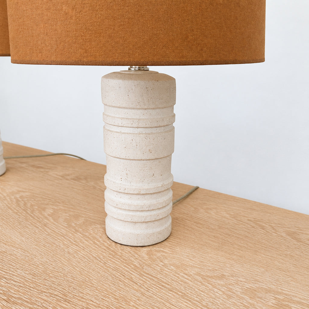 Two Shelter Brasilia Lamp by Modern Resale with textured white bases and orange cylindrical shades are displayed on a beige stone surface against a gray background.