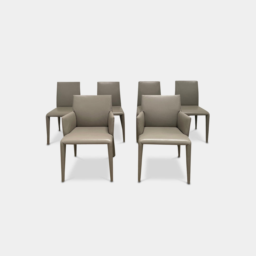 Six B&B Italia Vol au Vent Dining Chairs, embodying the elegance of Italian style, are arranged in two rows in an empty room with a concrete floor and a plain white wall.