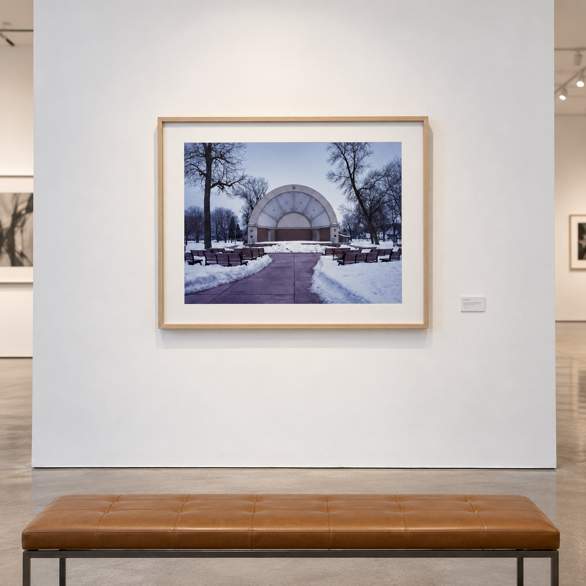 Framed Photograph - Metrostage by Cindy Bernard 2004 showing an outdoor bandshell in a snow-covered park with rows of empty benches.