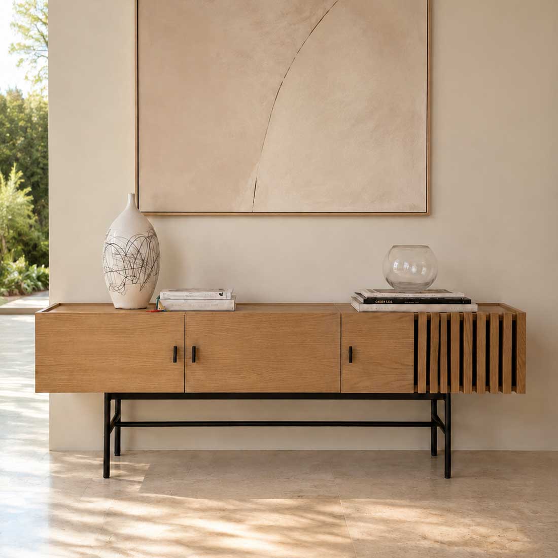 The Woud Array Low Sideboard White Pigmented Oak by Woud is a modern contemporary sideboard featuring three doors, sleek black metal legs, and elegant vertical slats on the right side. Crafted in white pigmented oak and presented against a plain white background, this piece brings stylish functionality to any interior.