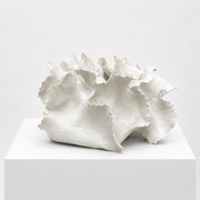 The Sofi Ceramics White Vessel Wave by Artist features ruffled, wavy edges and sits on a square pedestal, highlighting the elegance of handmade pottery against a simple background.