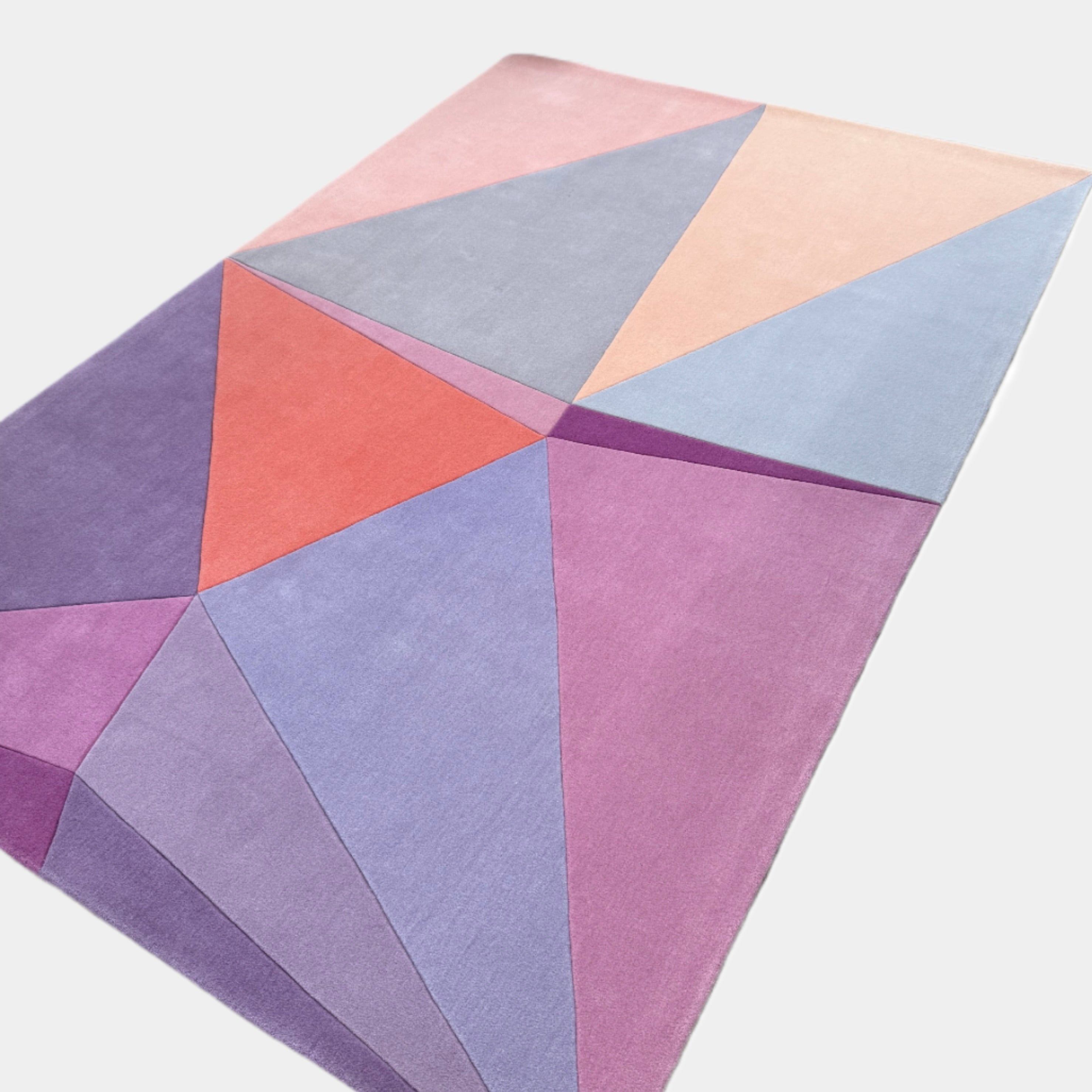 The Paul Smith Geometric Shape Split Rug Pastels features geometric designs in purple, pink, red, blue, and peach tones on a crisp white background.