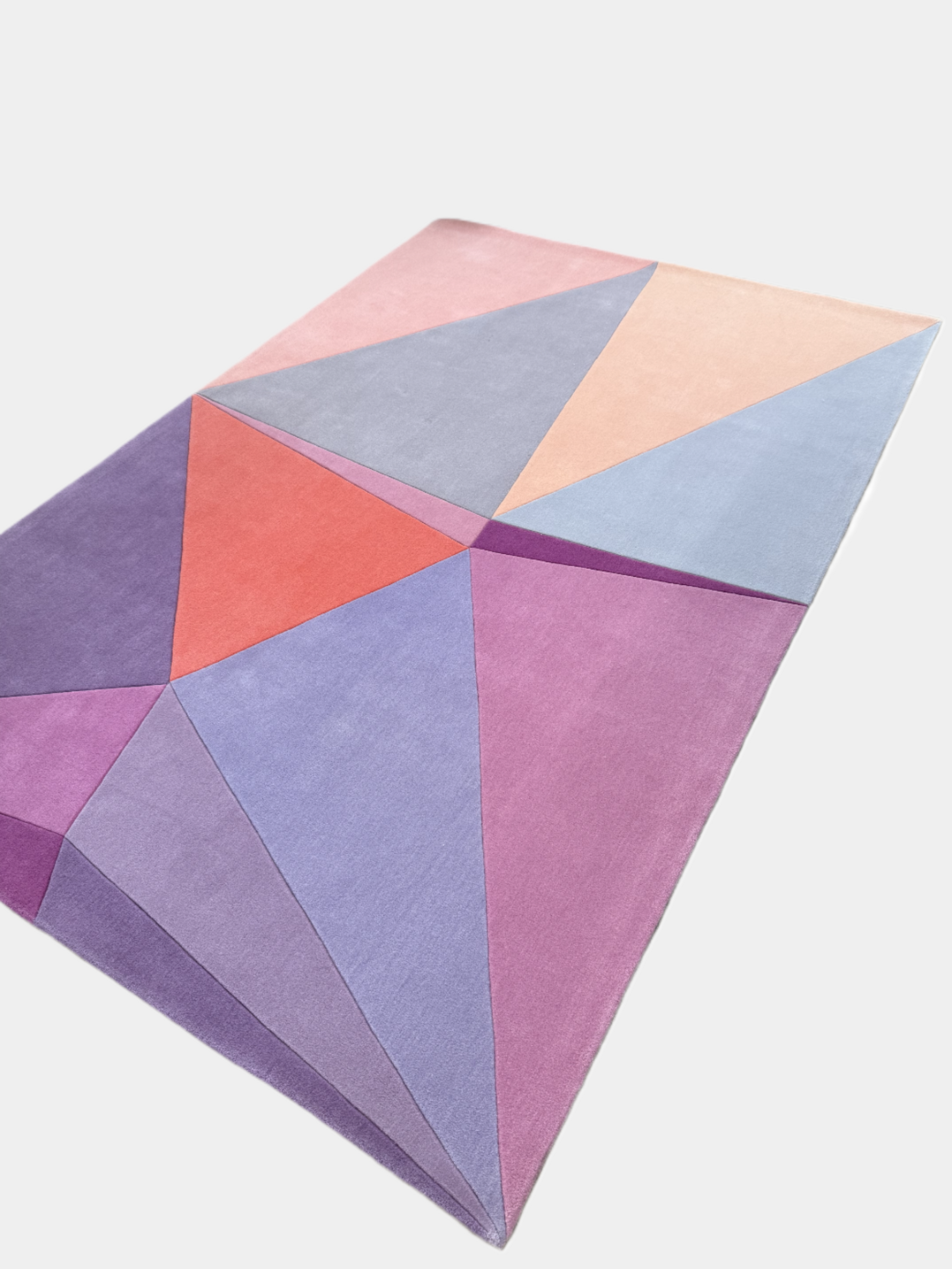 The Paul Smith Geometric Shape Split Rug Pastels features geometric designs in purple, pink, red, blue, and peach tones on a crisp white background.