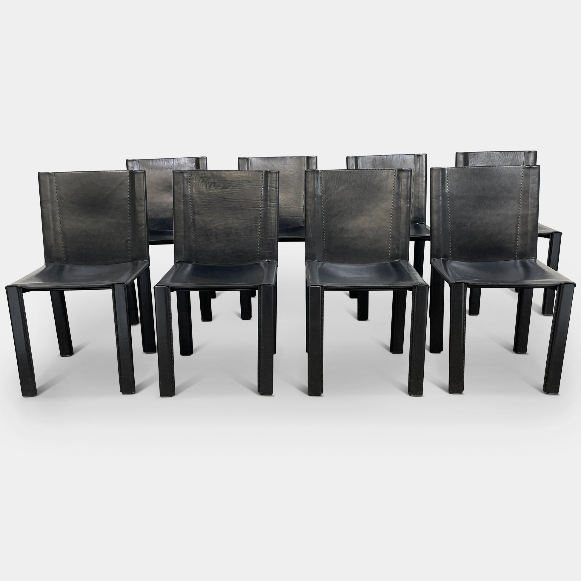 Eight Vintage Matteo Grassi 'Coral' dining chairs, showcasing a sleek black finish, are arranged in two rows on a pristine white background.