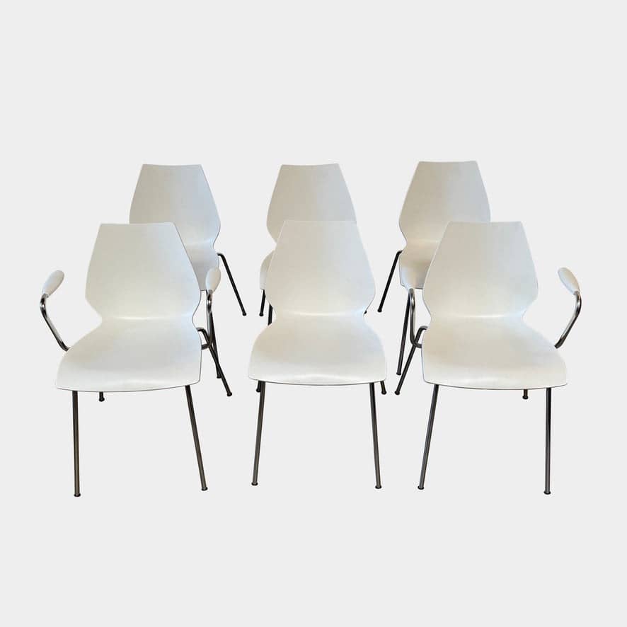 Six Kartell Maui chairs with and without armrests arranged in a row against a plain, light background.