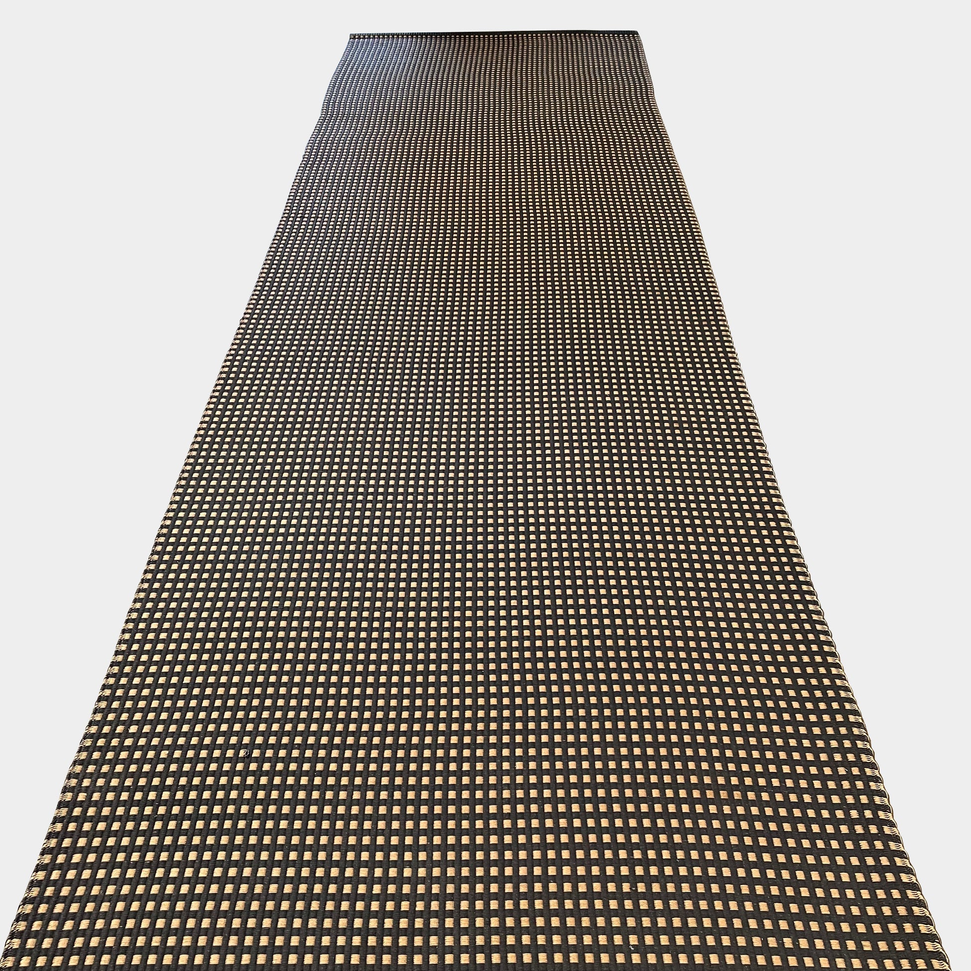An indoor/outdoor Woodnotes City Rug with cozy detail, in black and tan, on a white surface.
