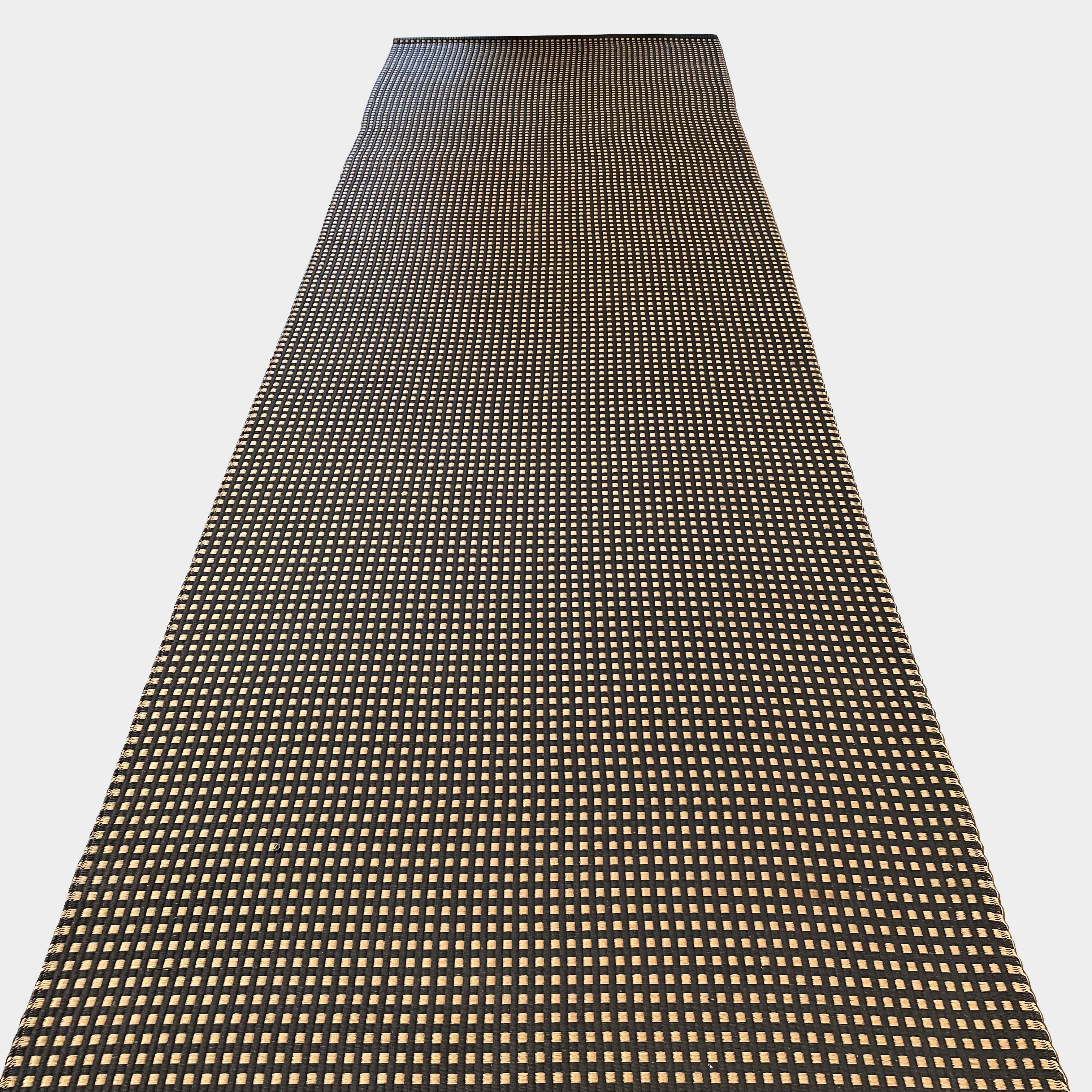 An indoor/outdoor Woodnotes City Rug with cozy detail, in black and tan, on a white surface.