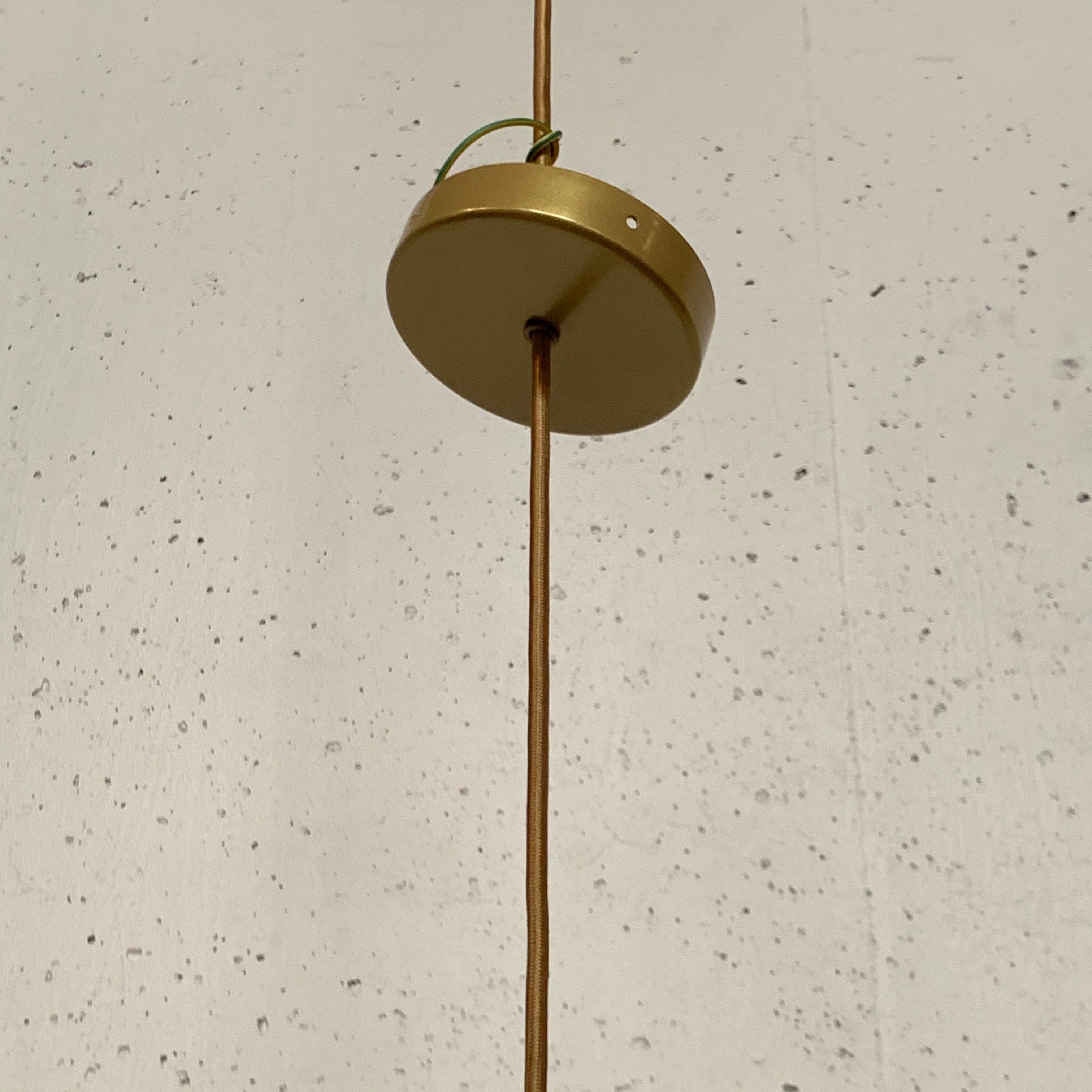 A modern suspension light featuring a white textured shade and a golden interior, suspended by a slender gold chain from Italian Vintage Ligne Roset Pharaoh Pendant.