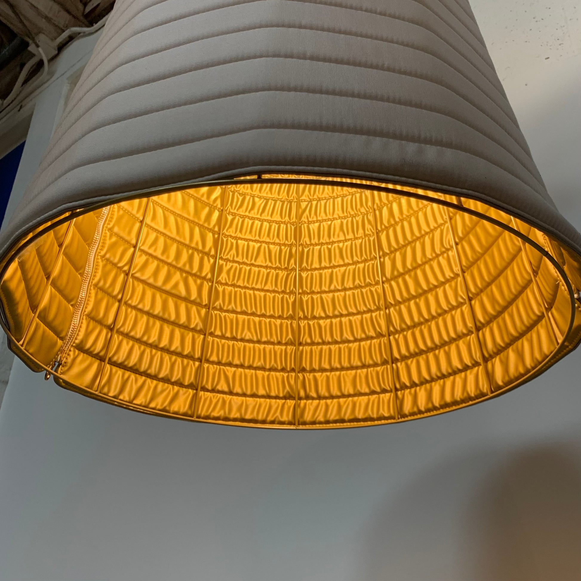 A modern suspension light featuring a white textured shade and a golden interior, suspended by a slender gold chain from Italian Vintage Ligne Roset Pharaoh Pendant.