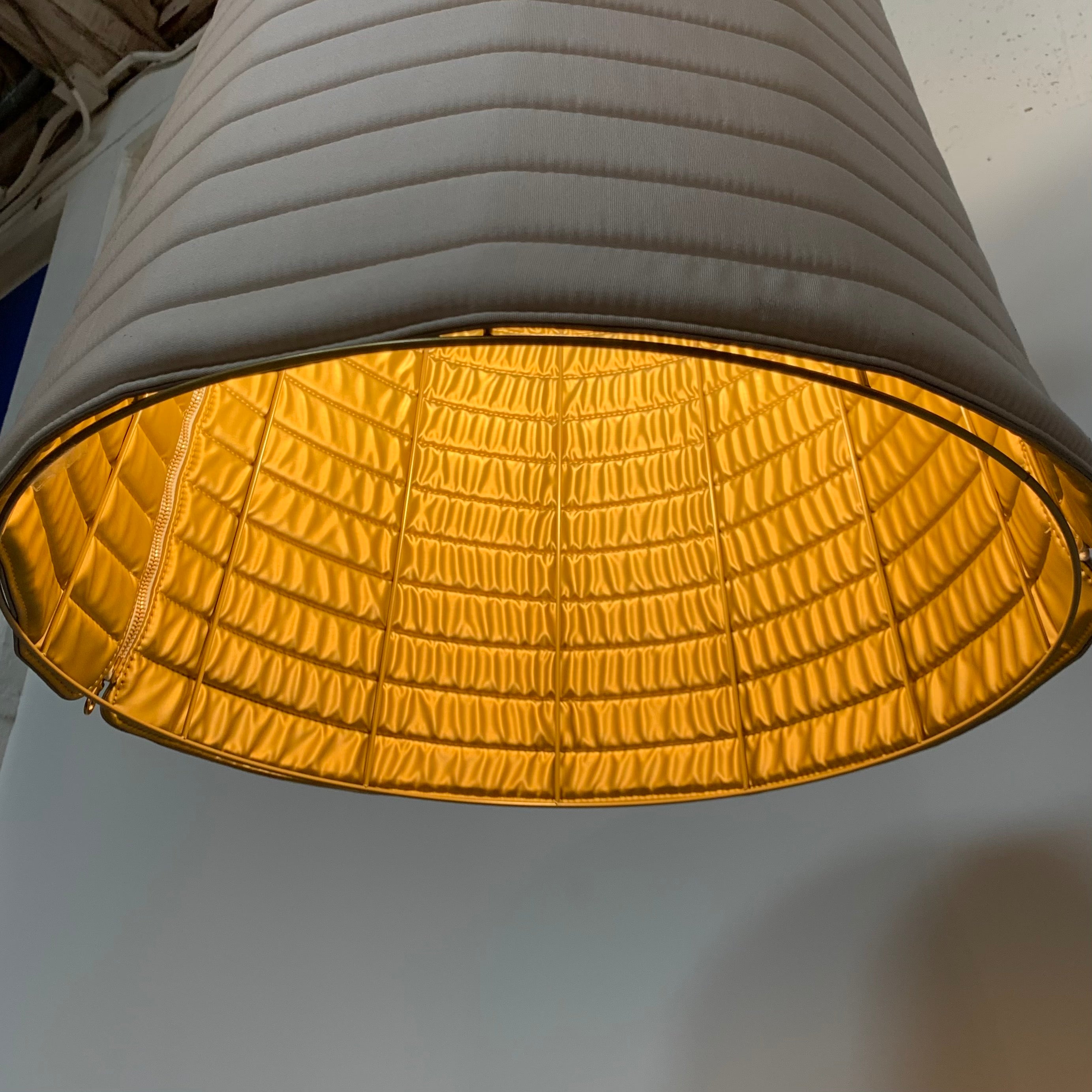 A modern suspension light featuring a white textured shade and a golden interior, suspended by a slender gold chain from Italian Vintage Ligne Roset Pharaoh Pendant.