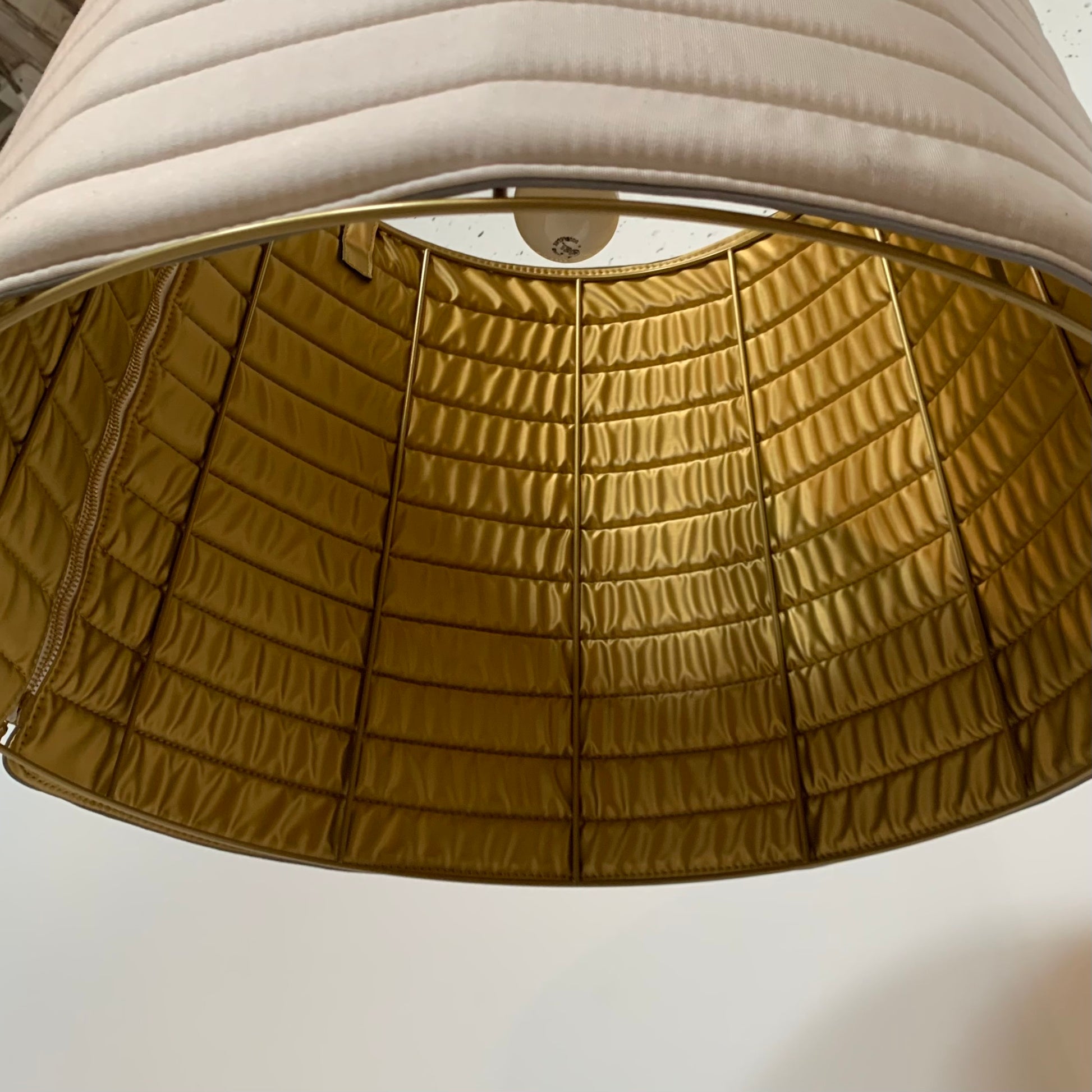 A modern suspension light featuring a white textured shade and a golden interior, suspended by a slender gold chain from Italian Vintage Ligne Roset Pharaoh Pendant.