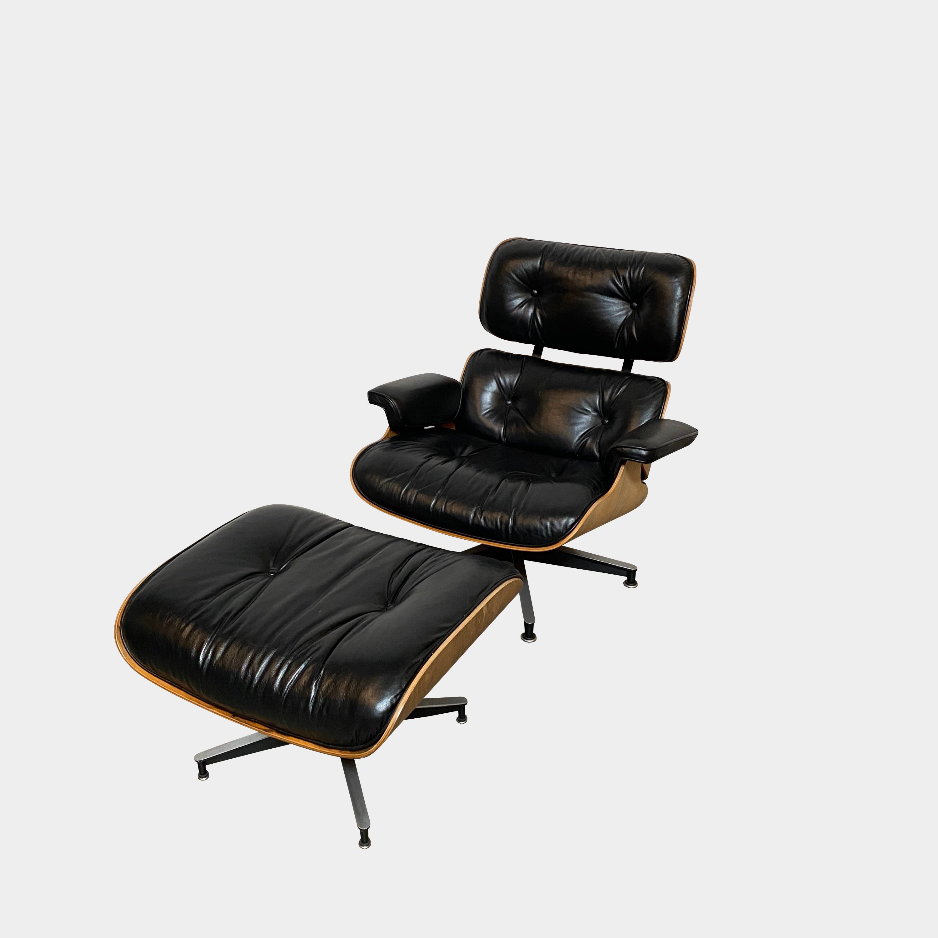 The MillerKnoll Herman Miller Eames Lounge Chair & Ottoman features black leather, wooden frames, and metal swivel bases, showcased against a white background—a timeless modern classic for sophisticated interiors.