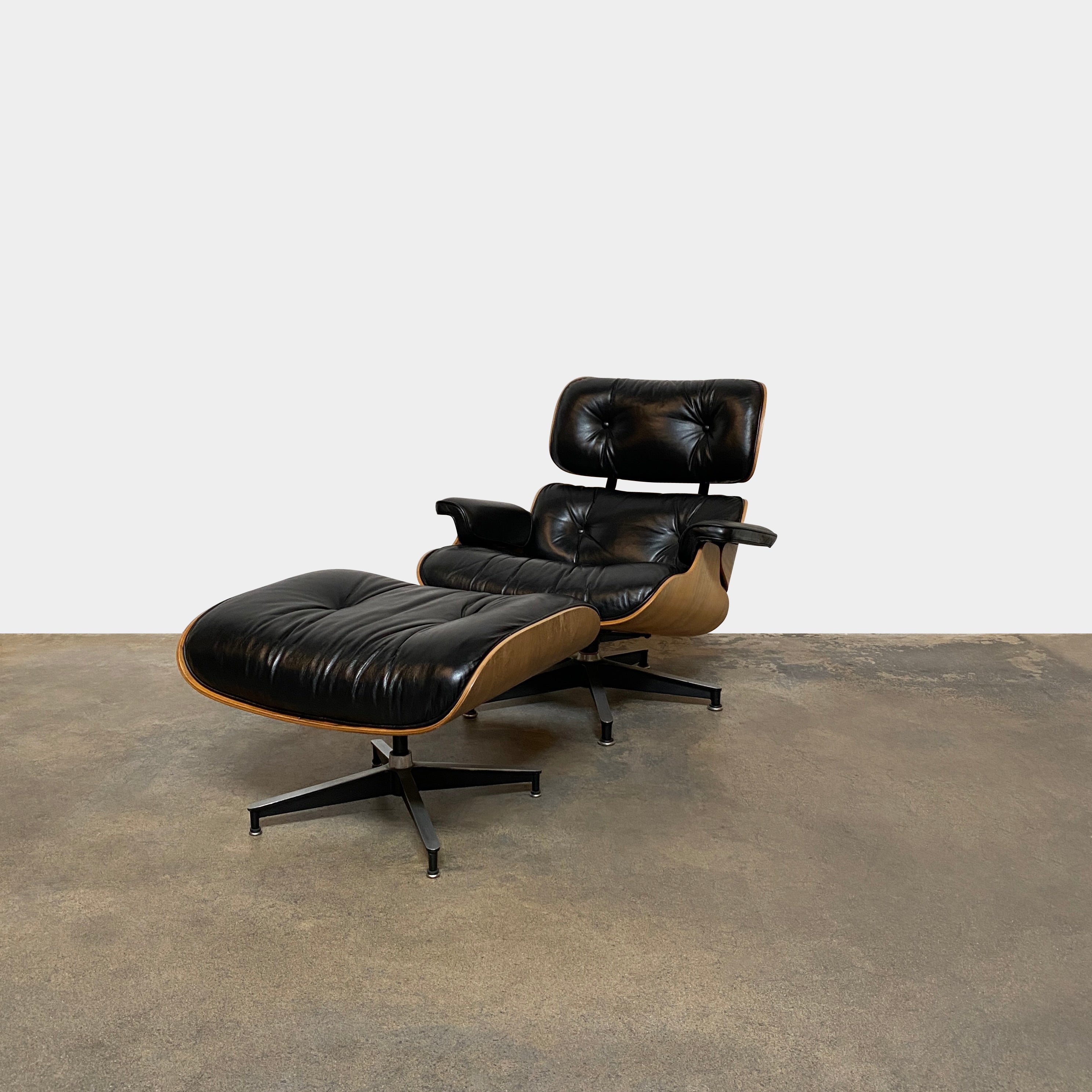 The MillerKnoll Herman Miller Eames Lounge Chair & Ottoman features black leather, wooden frames, and metal swivel bases, showcased against a white background—a timeless modern classic for sophisticated interiors.