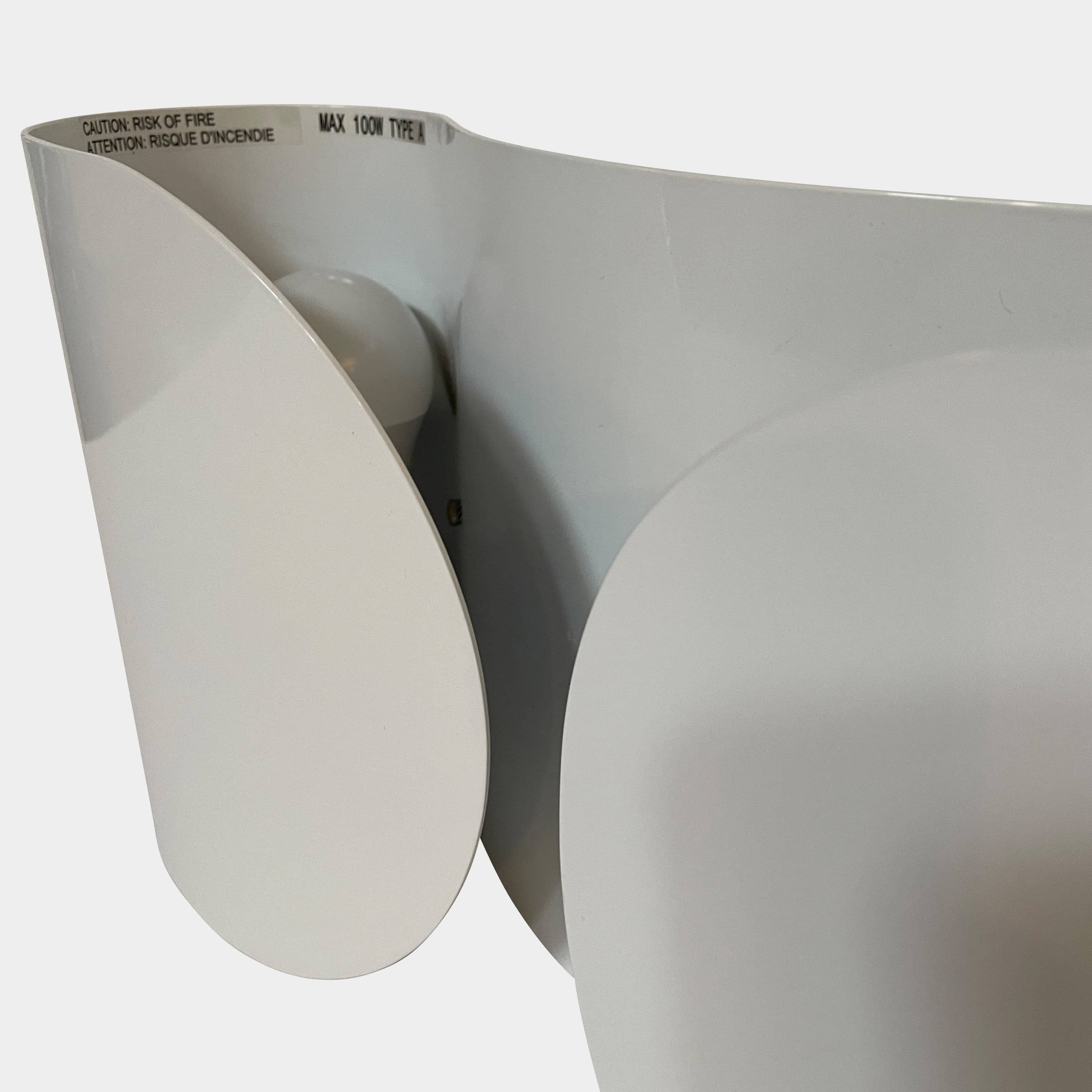 A set of Flos Foglio Wall Sconces emitting indirect light on a steel surface.