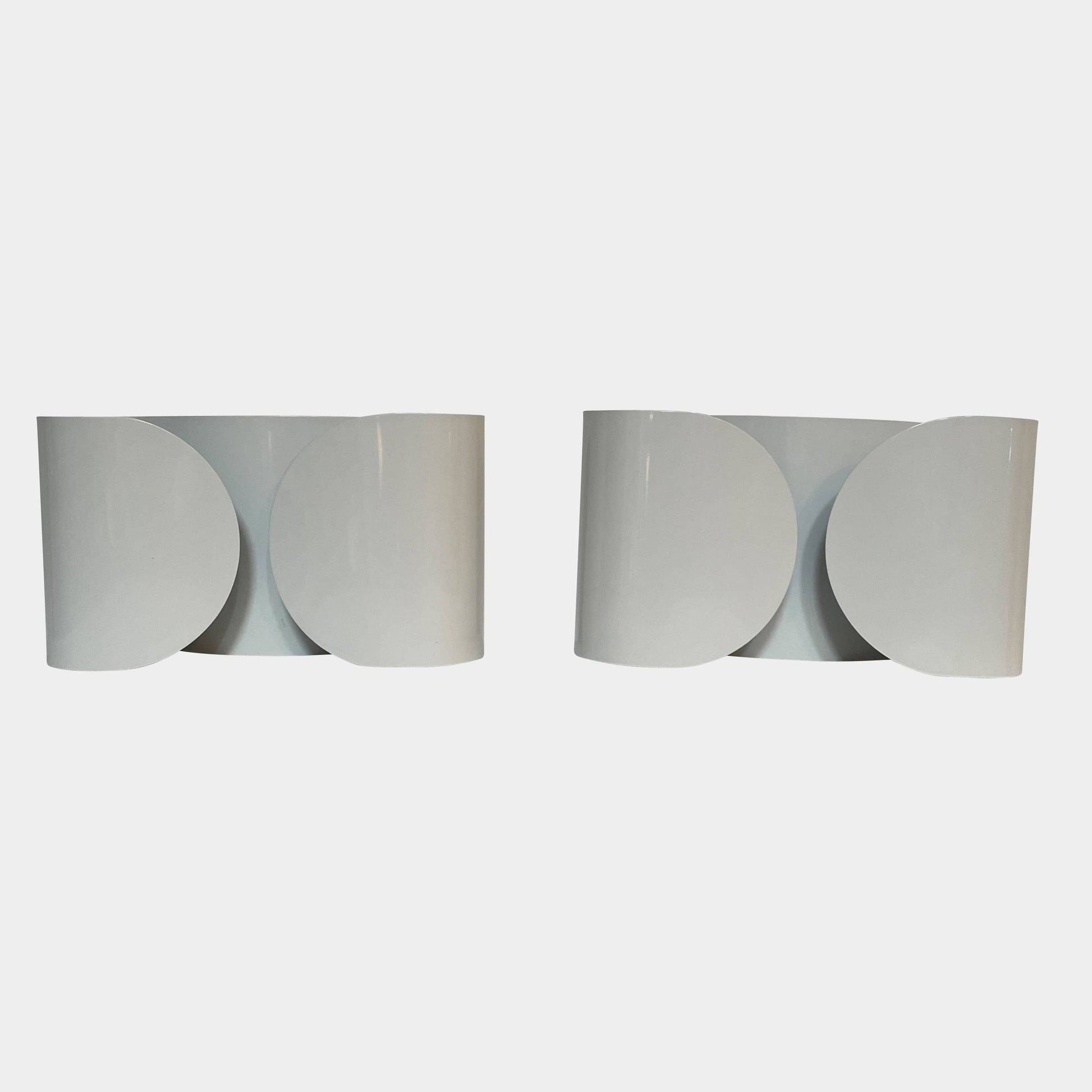 A set of Flos Foglio Wall Sconces emitting indirect light on a steel surface.