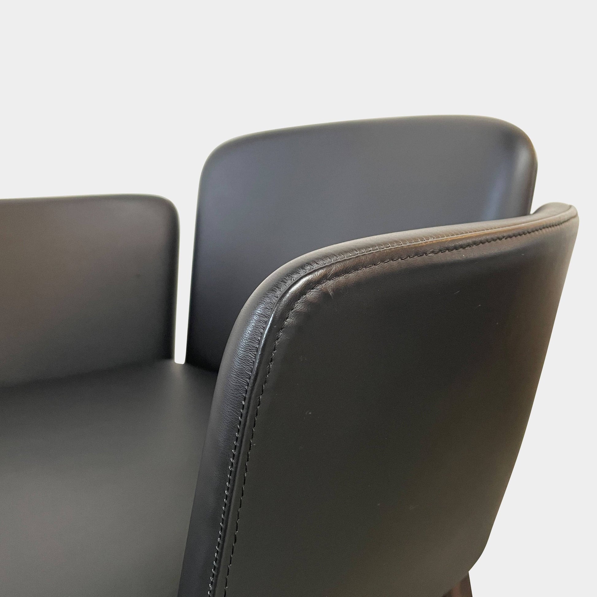 The Lema Tabby Leather Armchair by Lema features a black leather shell, accentuated by dark brown wood legs.