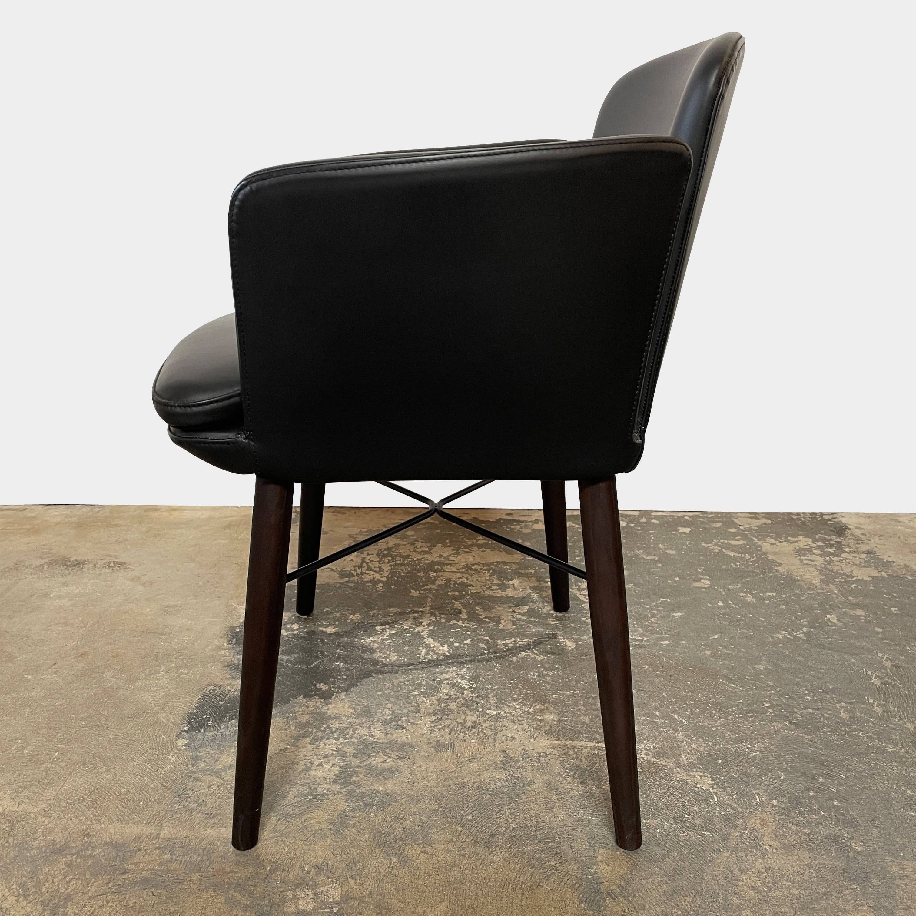 The Lema Tabby Leather Armchair by Lema features a black leather shell, accentuated by dark brown wood legs.