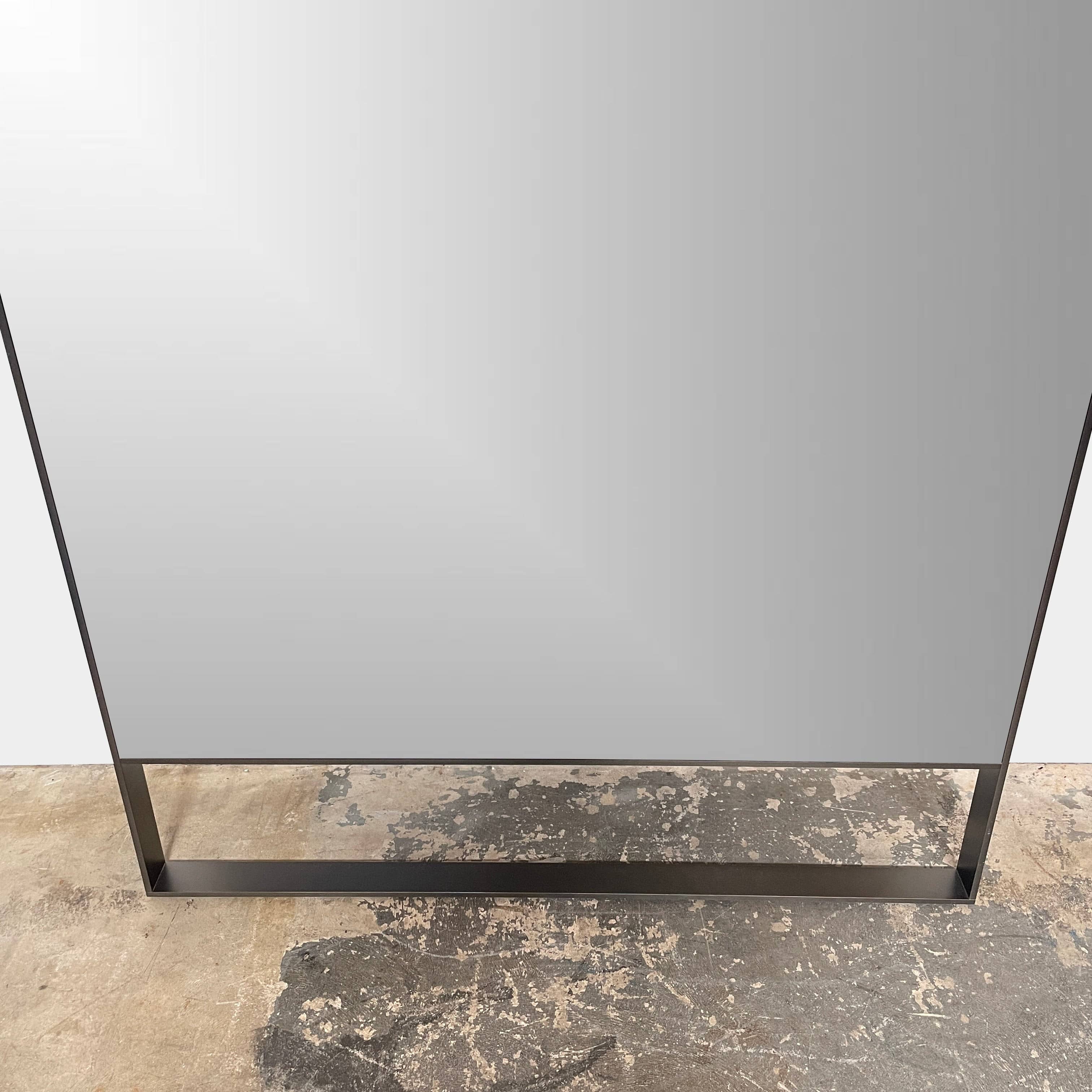 The Maxalto Psiche Leaning Mirror by Maxalto features a large rectangular shape, a slim dark frame, and a minimalist base, shown against a plain white background.