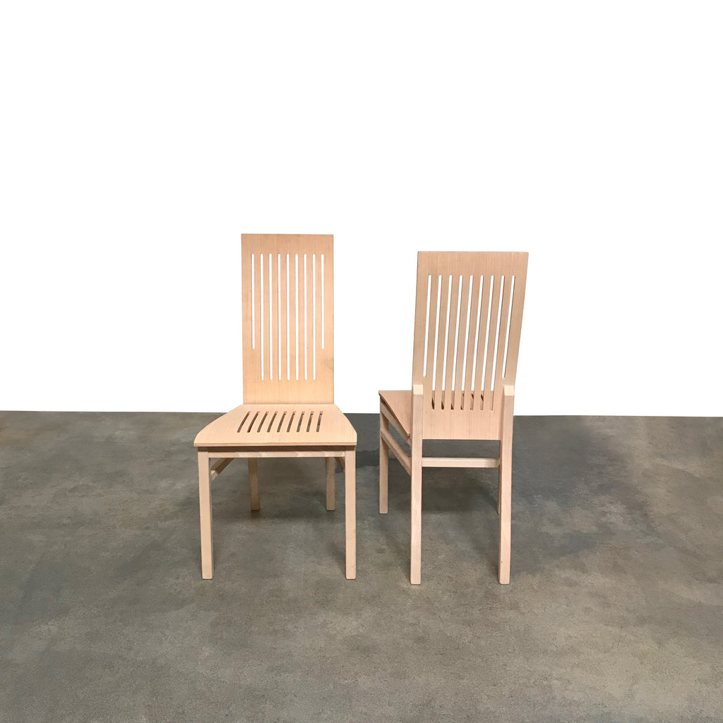 A Gramrode High-Back Dining Chair Set with slats against a concrete wall, exuding a beachy vibe reminiscent of the California lifestyle.