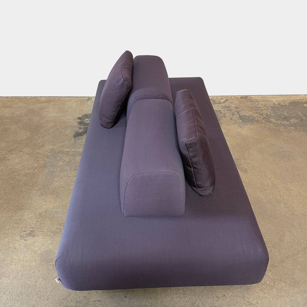 A Paola Lenti Orlando Outdoor Sofa with two pillows in a dark blue color.