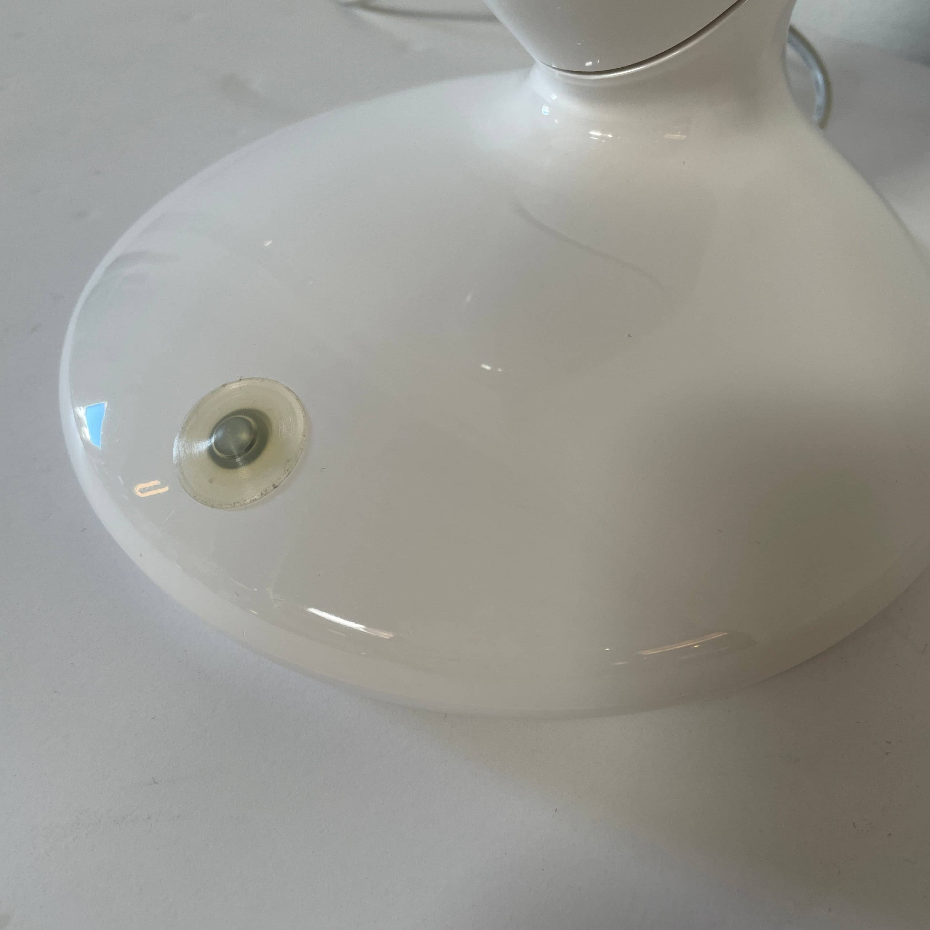 A modern white desk lamp with a curved design and a round base, reminiscent of Ross Lovegrove's aesthetic, akin to the elegance of Yamagiwa Geon Task Lights by Yamagiwa.