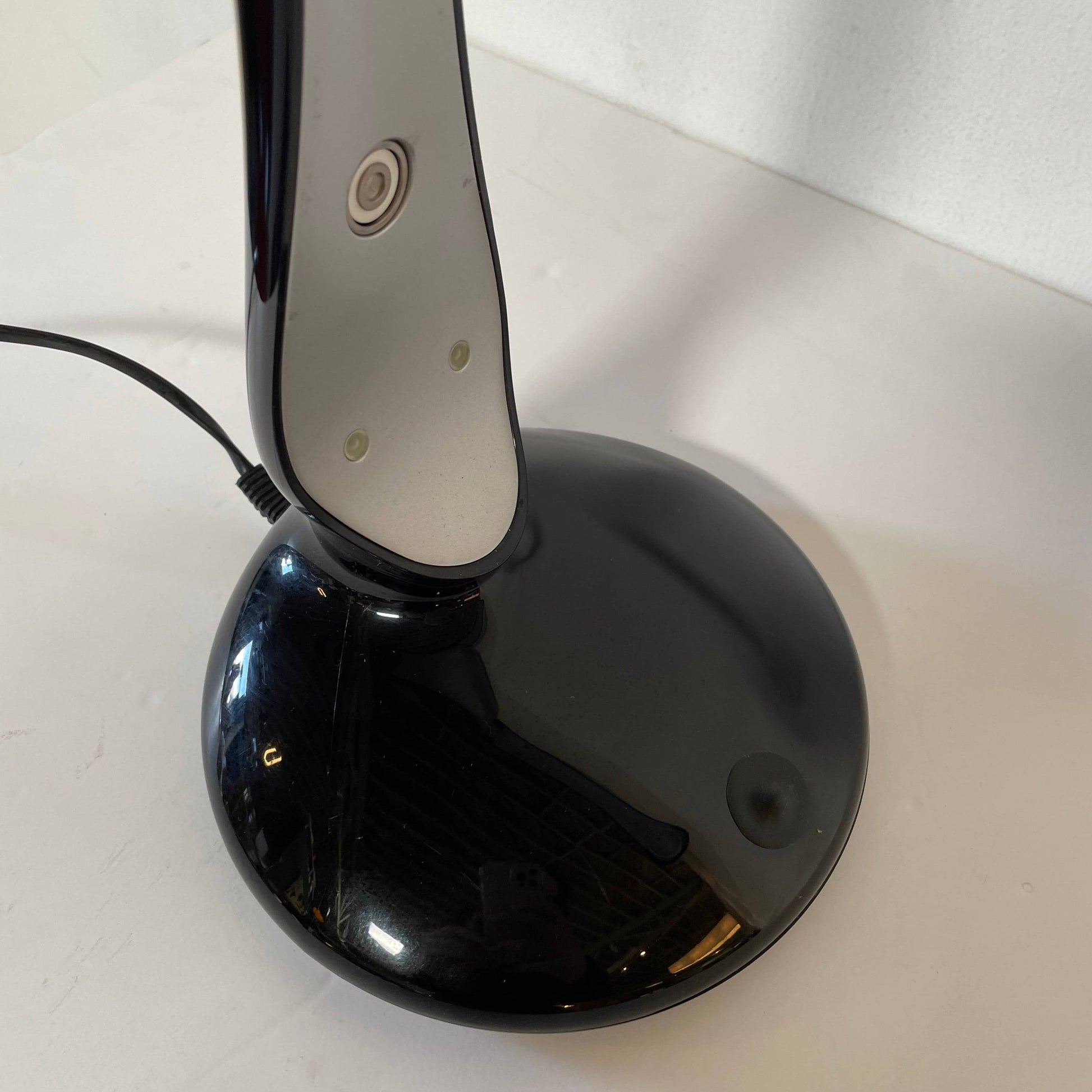 A modern white desk lamp with a curved design and a round base, reminiscent of Ross Lovegrove's aesthetic, akin to the elegance of Yamagiwa Geon Task Lights by Yamagiwa.