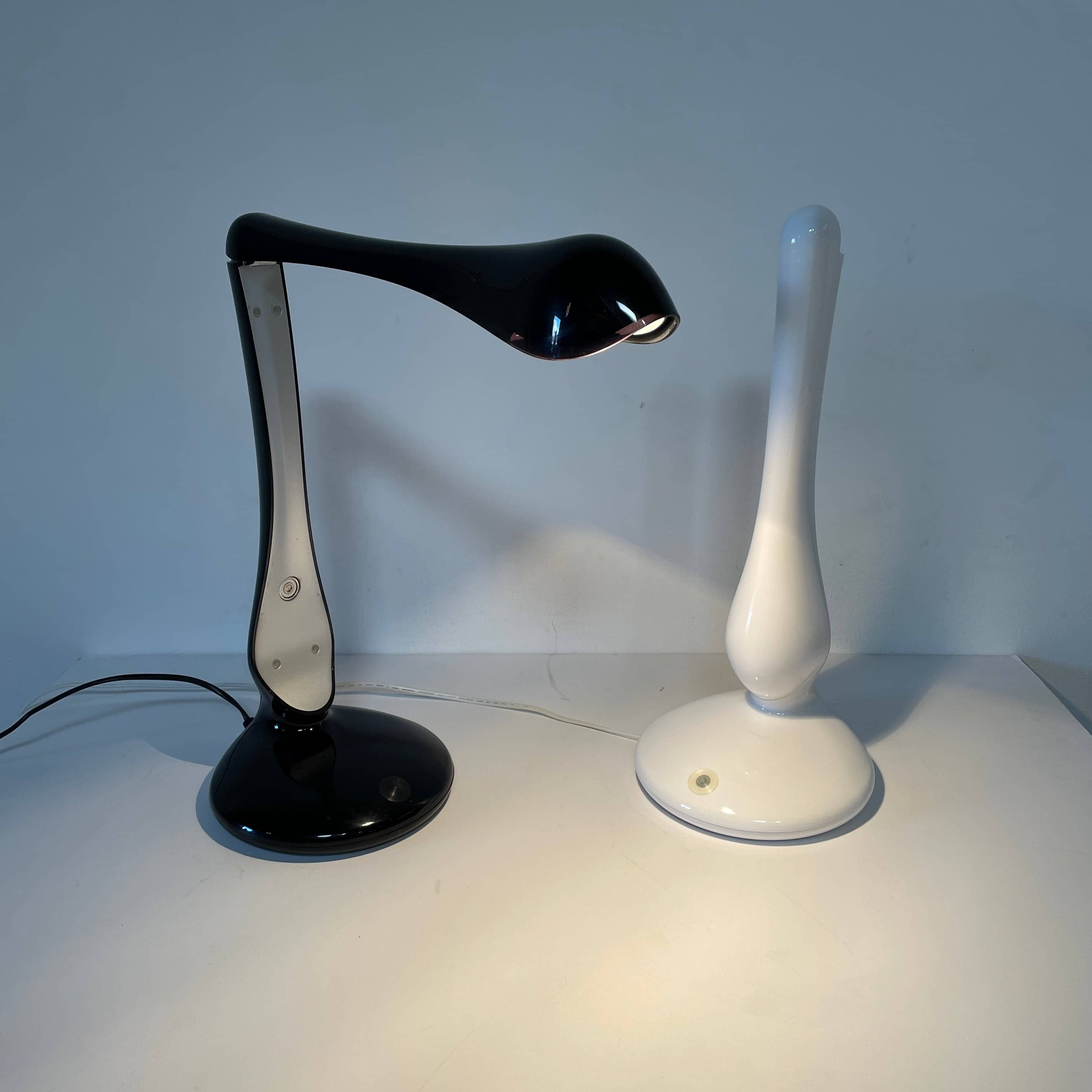 A modern white desk lamp with a curved design and a round base, reminiscent of Ross Lovegrove's aesthetic, akin to the elegance of Yamagiwa Geon Task Lights by Yamagiwa.