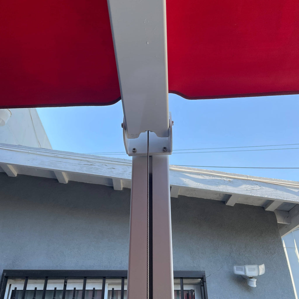 A red Crema Diomede outdoor umbrella on a stand with a white background.