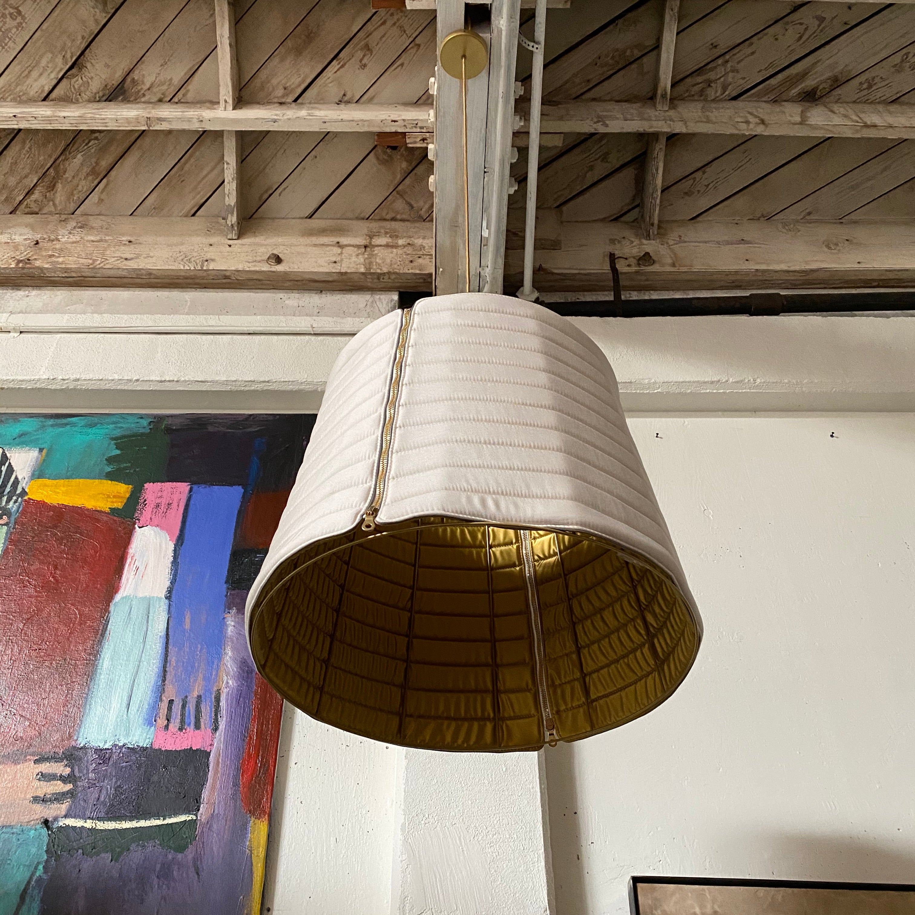 A modern suspension light featuring a white textured shade and a golden interior, suspended by a slender gold chain from Italian Vintage Ligne Roset Pharaoh Pendant.