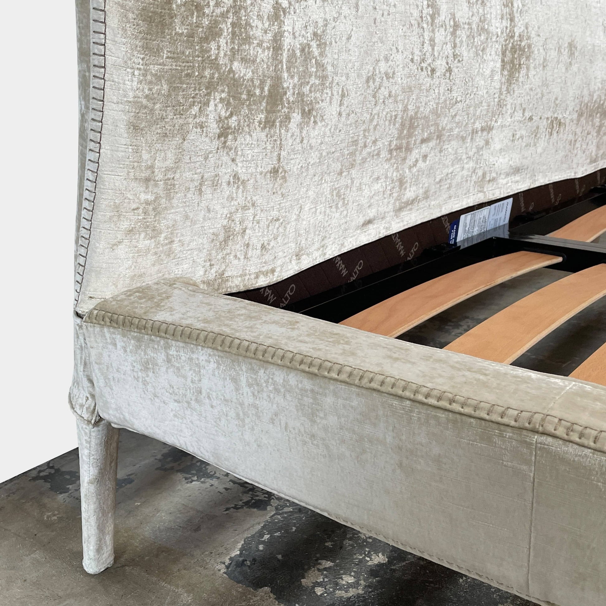 The Maxalto Febo Queen Bed is an upholstered bed frame featuring a headboard and two pillows, all elegantly wrapped in champagne-colored velvet. The frame boasts wooden slats for support, providing the refined touch of a luxury hotel bed. Shown without a mattress.