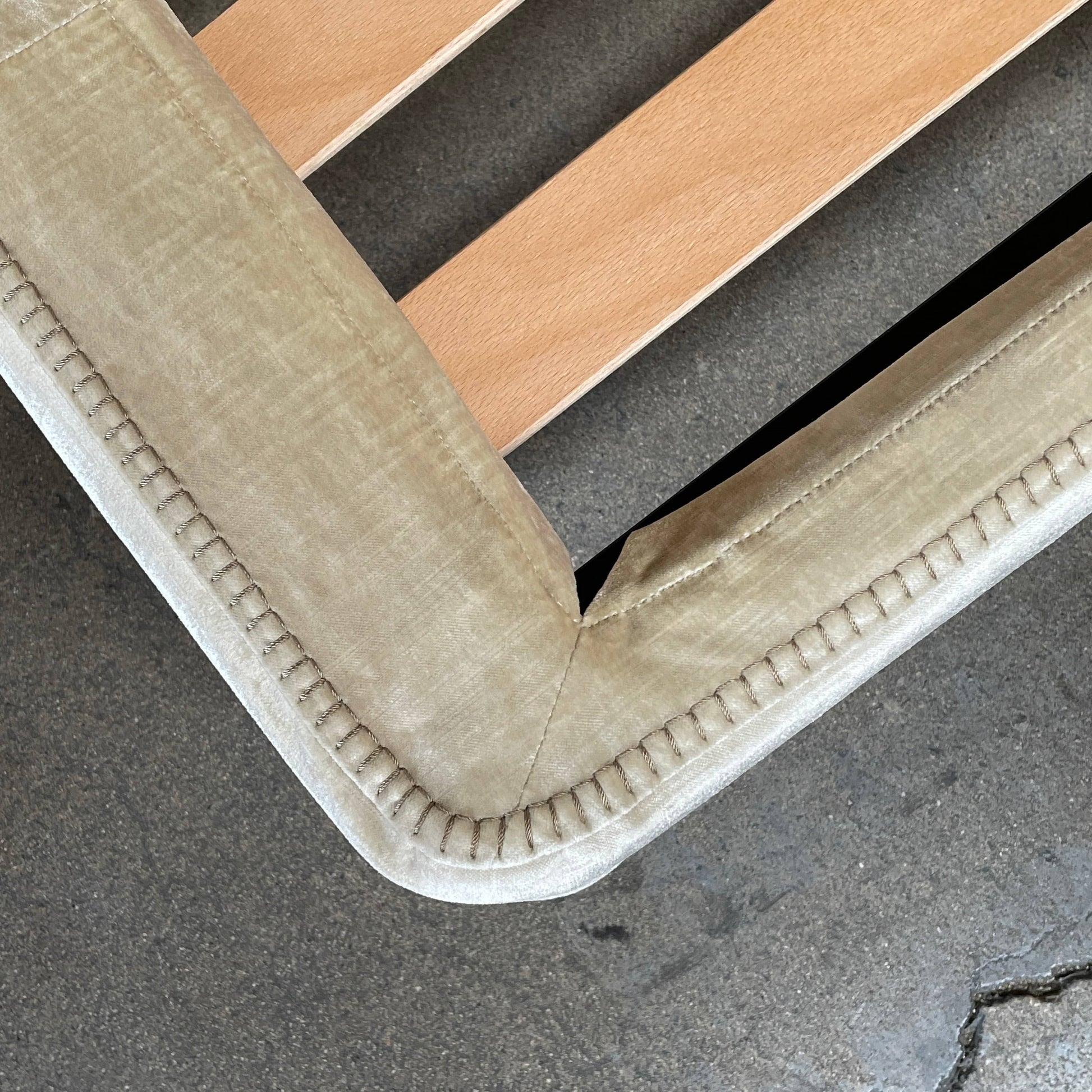 The Maxalto Febo Queen Bed is an upholstered bed frame featuring a headboard and two pillows, all elegantly wrapped in champagne-colored velvet. The frame boasts wooden slats for support, providing the refined touch of a luxury hotel bed. Shown without a mattress.