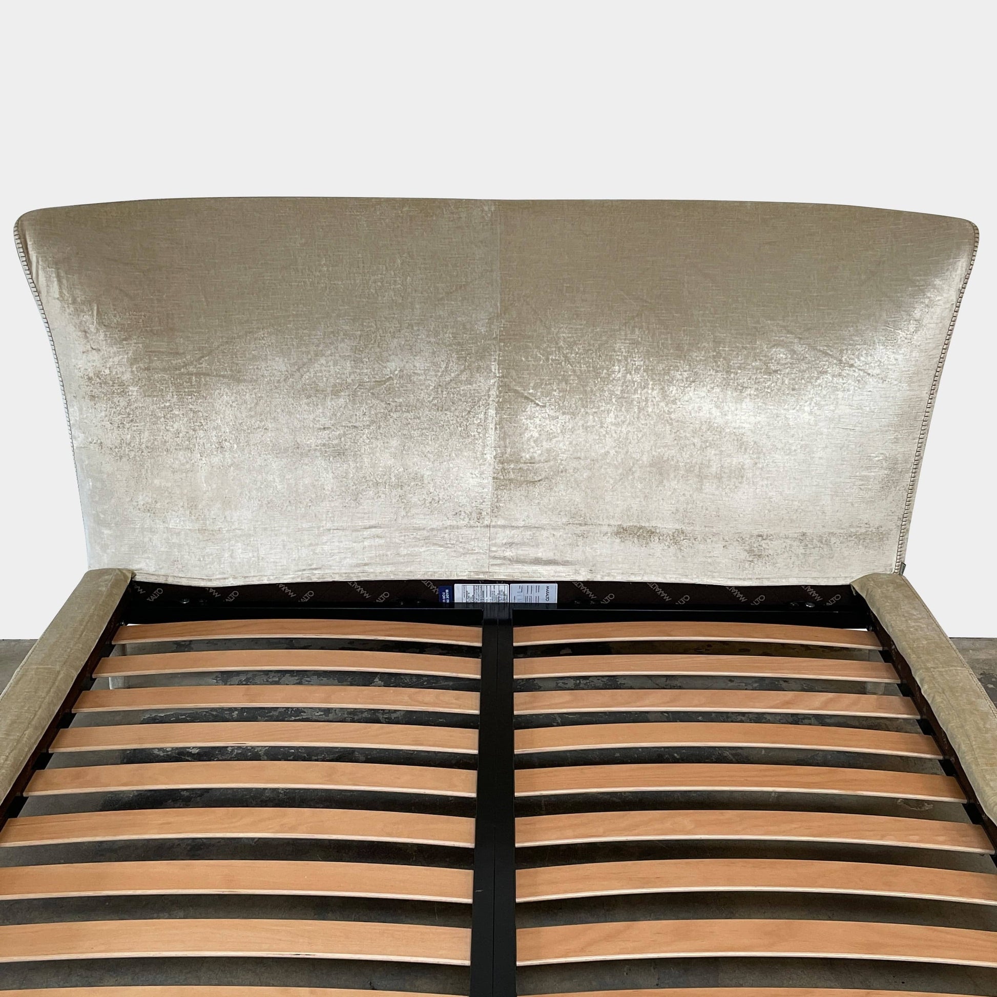 The Maxalto Febo Queen Bed is an upholstered bed frame featuring a headboard and two pillows, all elegantly wrapped in champagne-colored velvet. The frame boasts wooden slats for support, providing the refined touch of a luxury hotel bed. Shown without a mattress.