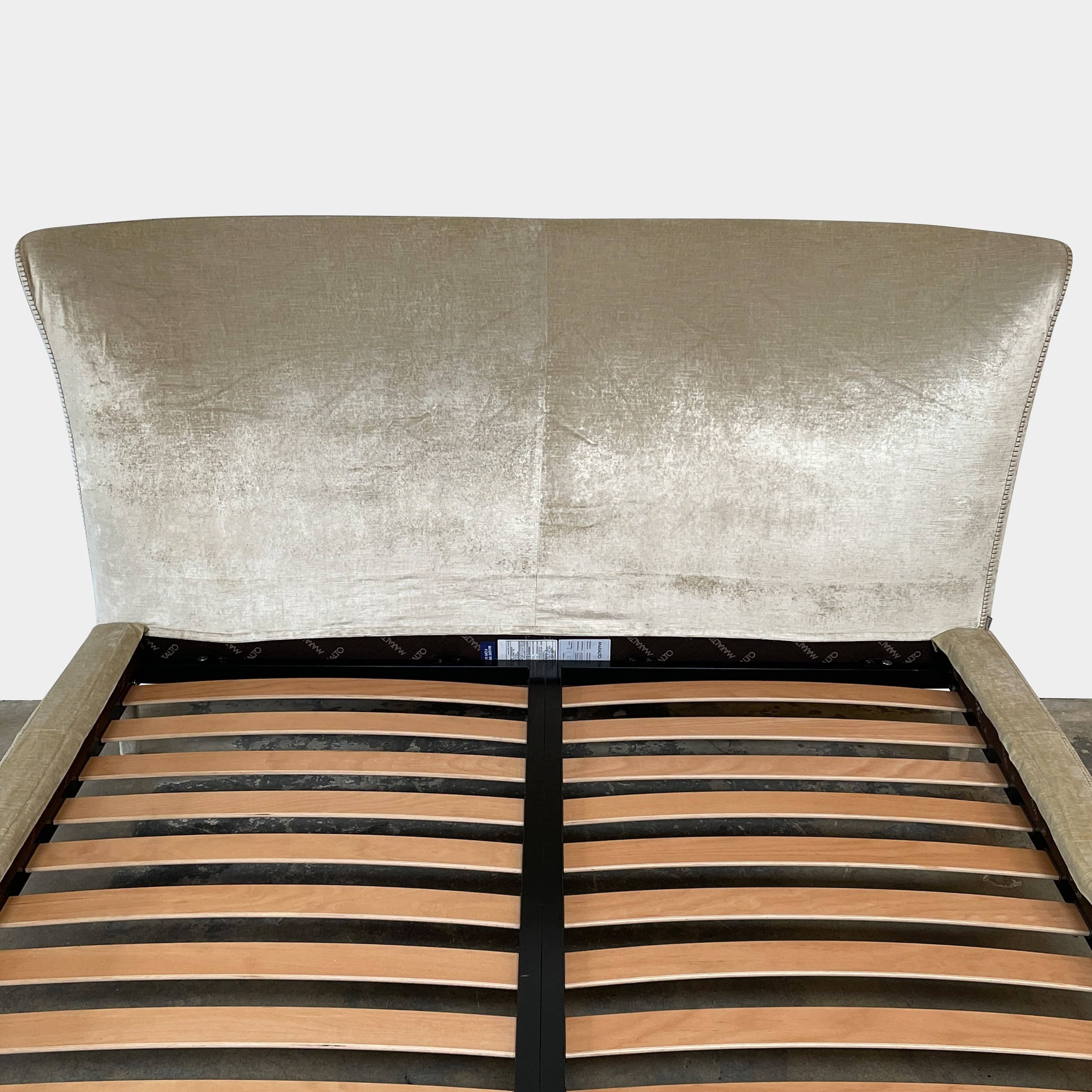 The Maxalto Febo Queen Bed is an upholstered bed frame featuring a headboard and two pillows, all elegantly wrapped in champagne-colored velvet. The frame boasts wooden slats for support, providing the refined touch of a luxury hotel bed. Shown without a mattress.