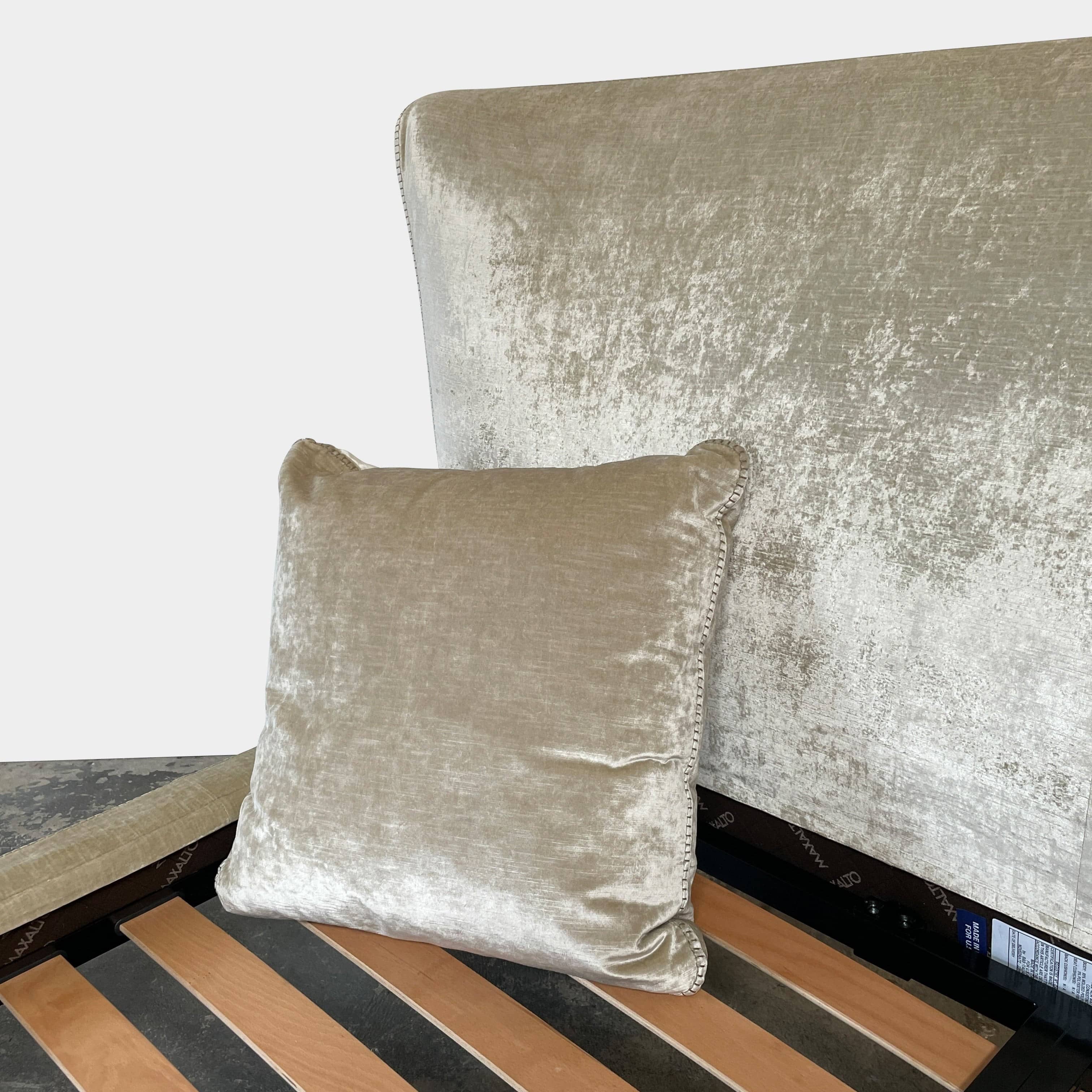 The Maxalto Febo Queen Bed is an upholstered bed frame featuring a headboard and two pillows, all elegantly wrapped in champagne-colored velvet. The frame boasts wooden slats for support, providing the refined touch of a luxury hotel bed. Shown without a mattress.