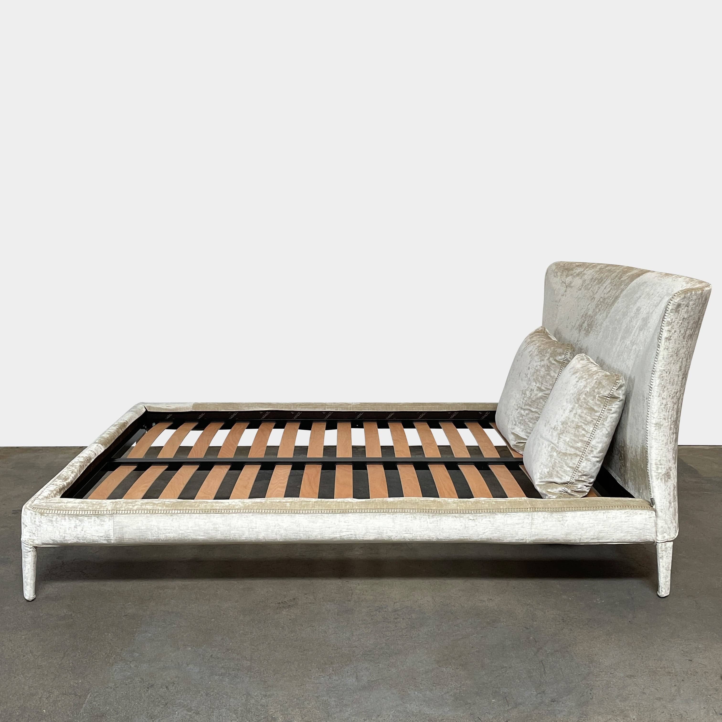 The Maxalto Febo Queen Bed is an upholstered bed frame featuring a headboard and two pillows, all elegantly wrapped in champagne-colored velvet. The frame boasts wooden slats for support, providing the refined touch of a luxury hotel bed. Shown without a mattress.