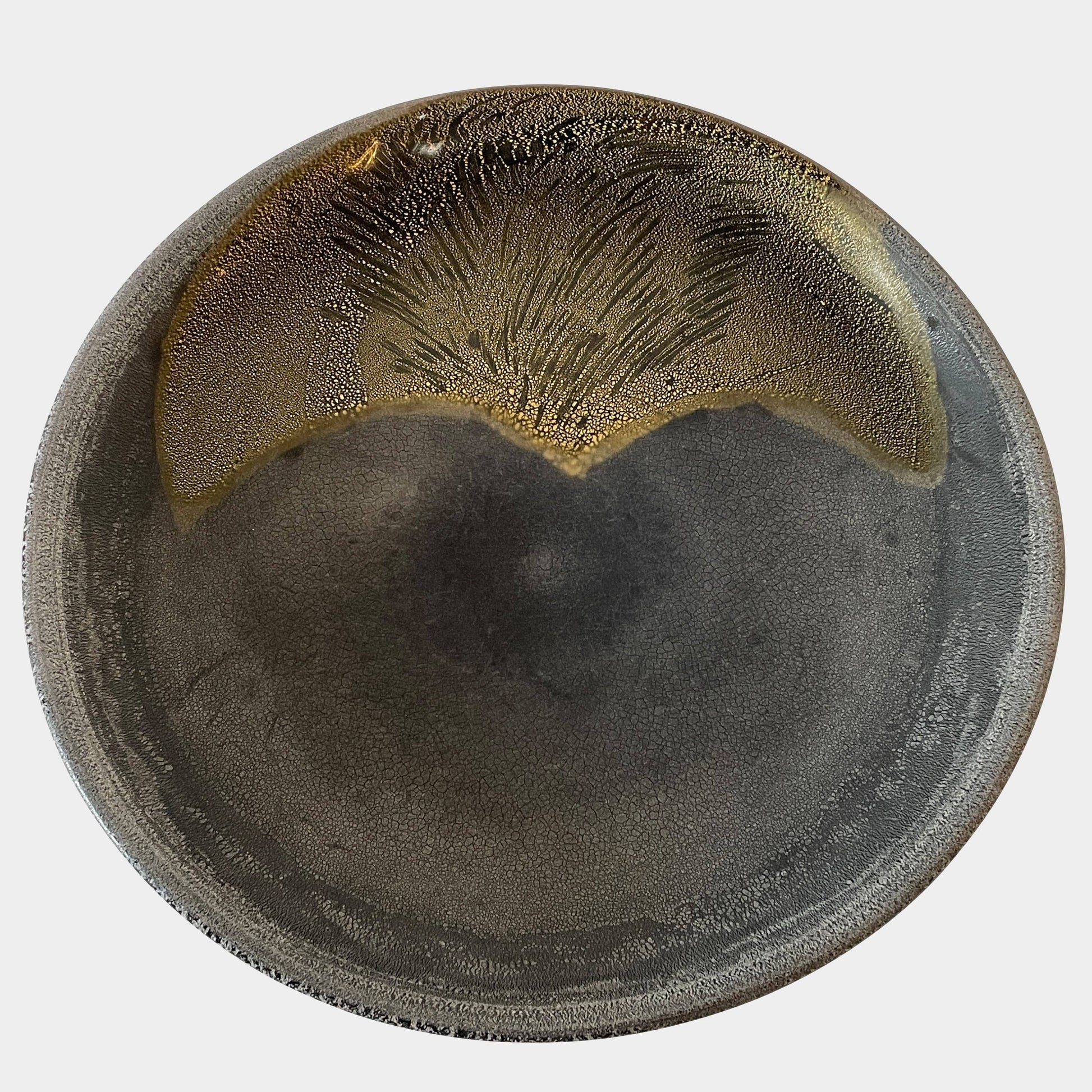 A round ceramic plate featuring a central raised circular design, predominantly gray with earthy bronze tones and textured streaks on one side, reminiscent of the artistry seen in the Alfredo Barbini Murano Glass Plate And Object.