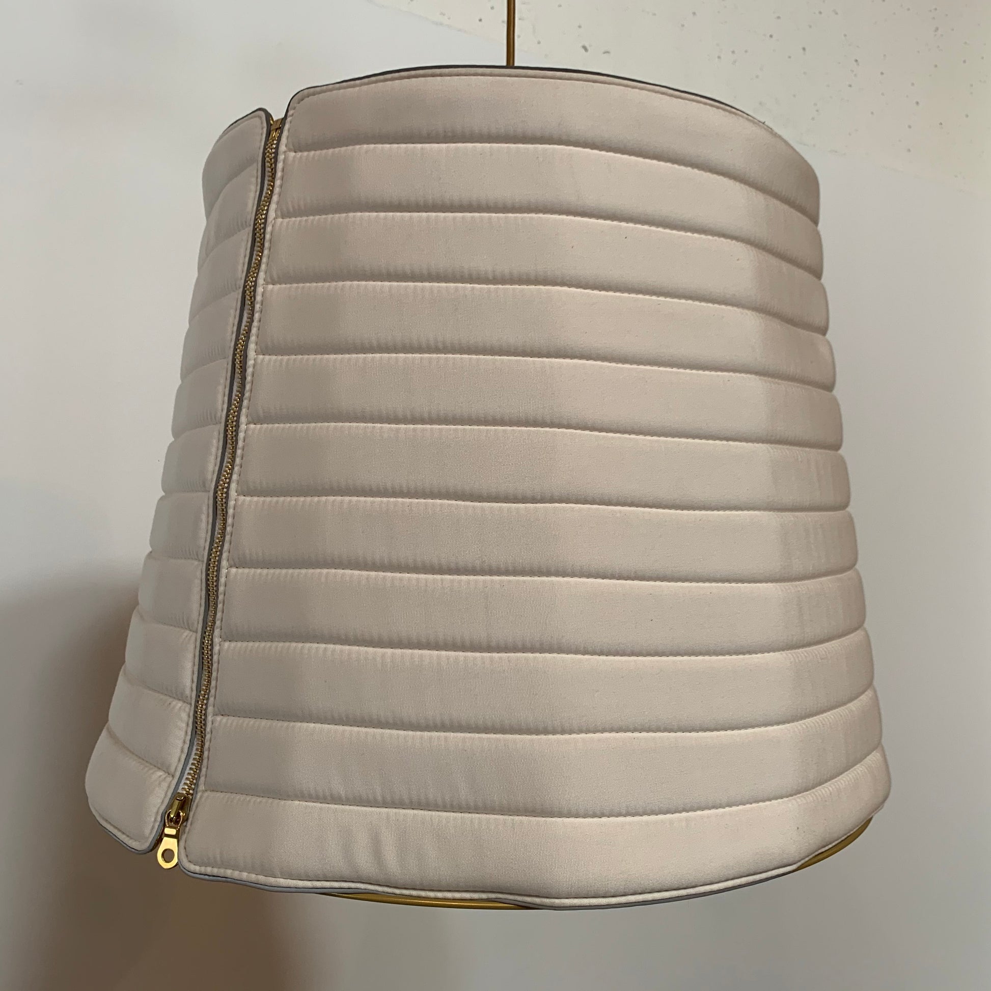 A modern suspension light featuring a white textured shade and a golden interior, suspended by a slender gold chain from Italian Vintage Ligne Roset Pharaoh Pendant.