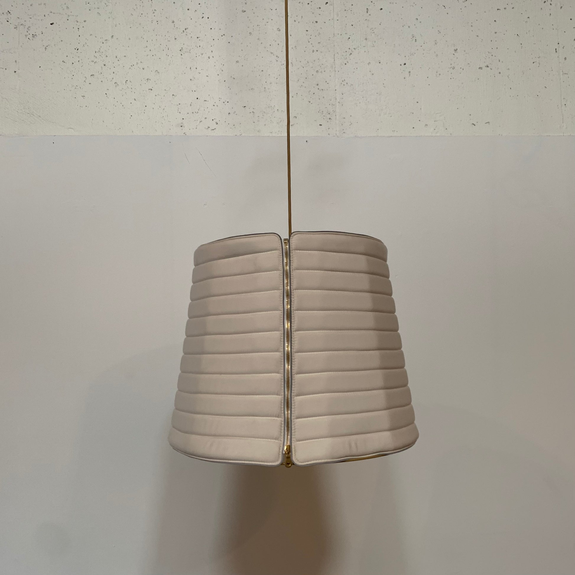 A modern suspension light featuring a white textured shade and a golden interior, suspended by a slender gold chain from Italian Vintage Ligne Roset Pharaoh Pendant.