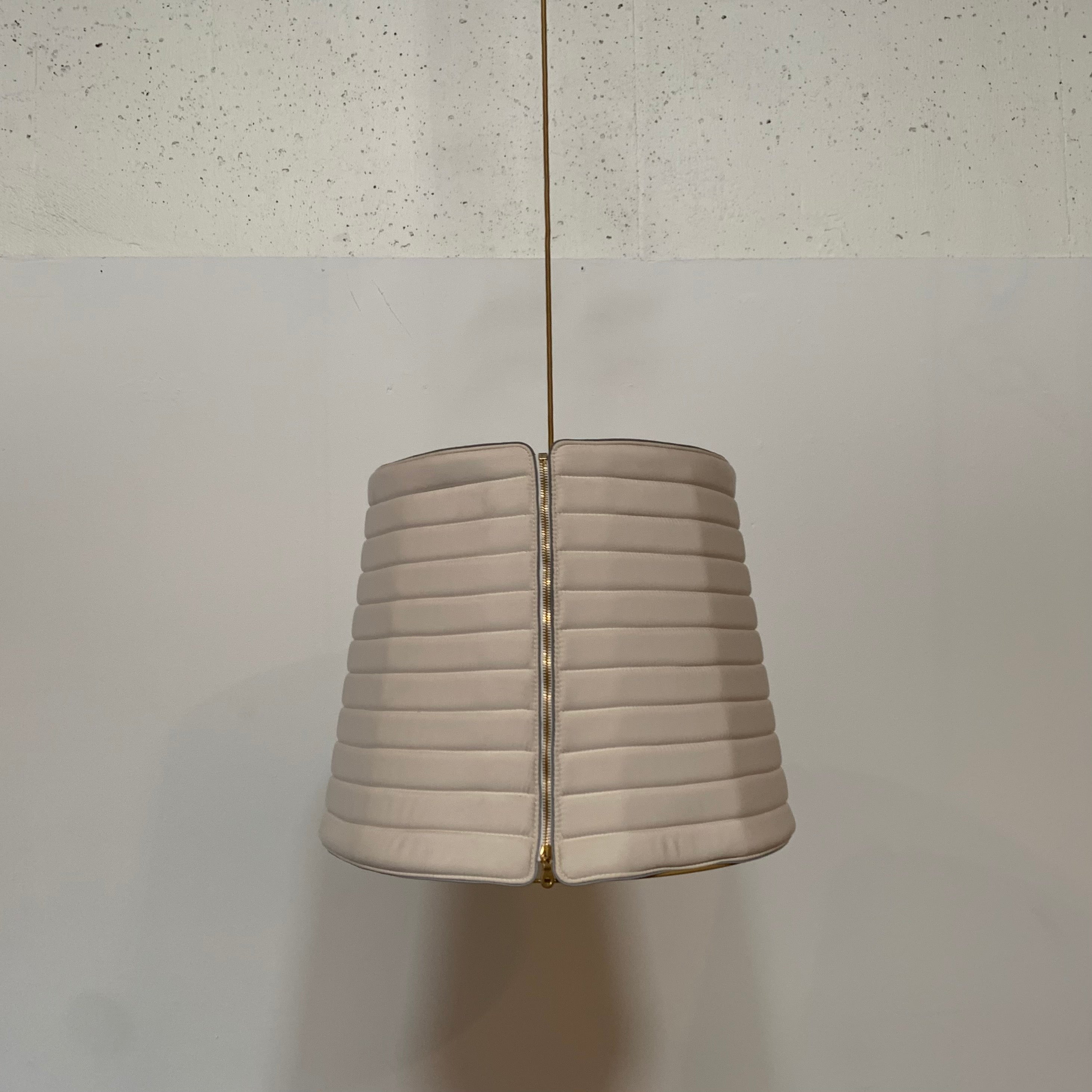 A modern suspension light featuring a white textured shade and a golden interior, suspended by a slender gold chain from Italian Vintage Ligne Roset Pharaoh Pendant.