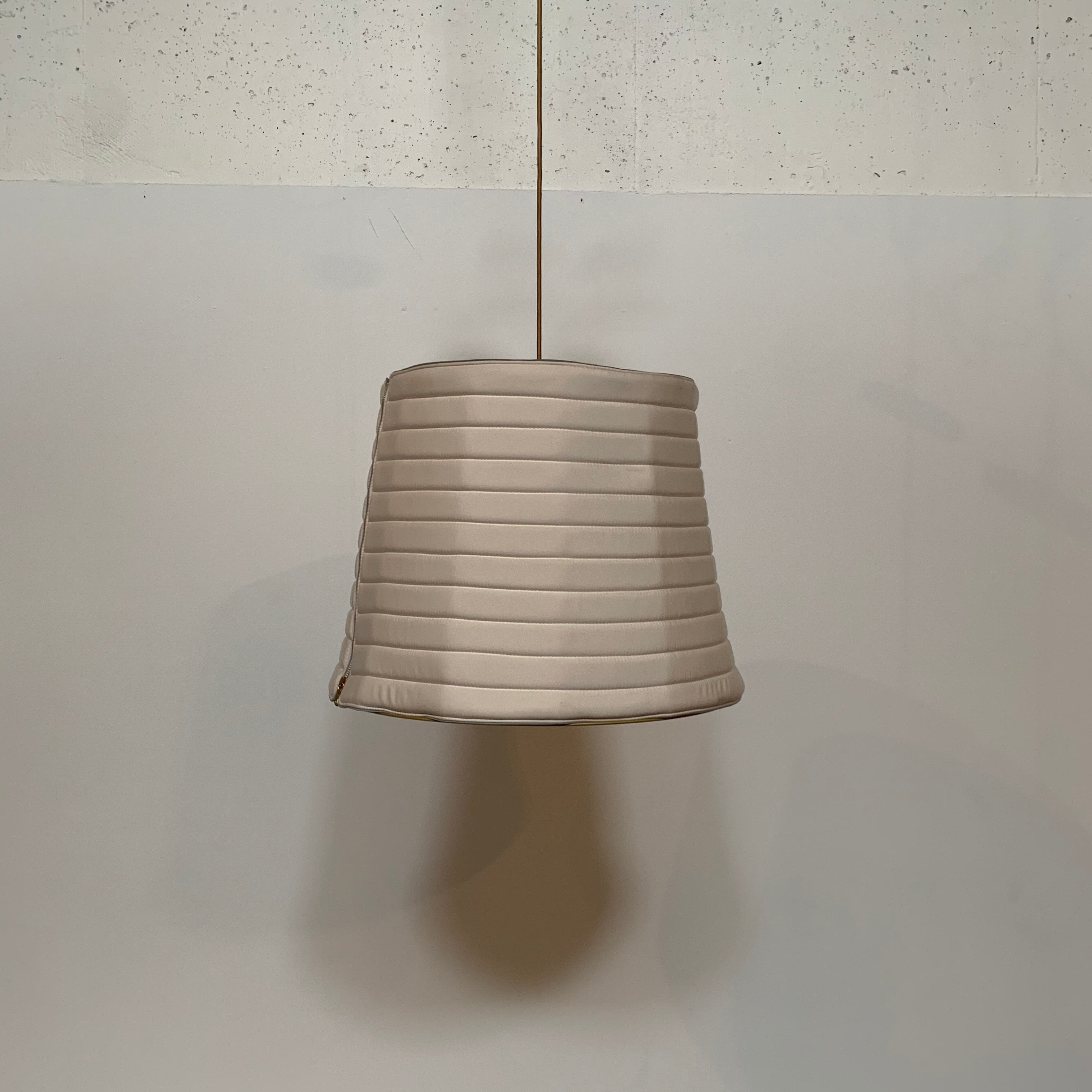 A modern suspension light featuring a white textured shade and a golden interior, suspended by a slender gold chain from Italian Vintage Ligne Roset Pharaoh Pendant.