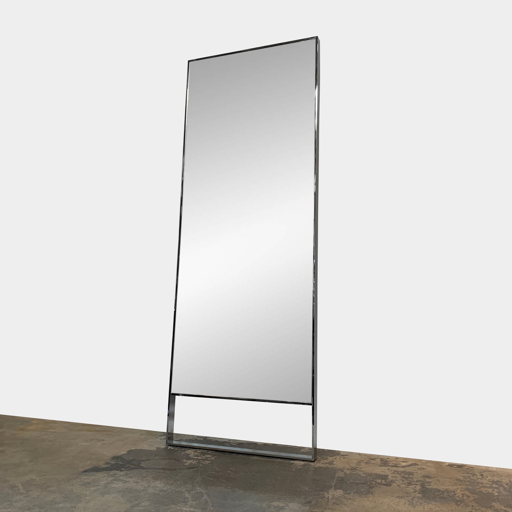 The Maxalto Psiche Mirror SMS1 Chrome, featuring a slim metallic frame, stands upright against a plain light gray background, reflecting the signature elegance of the Maxalto brand.