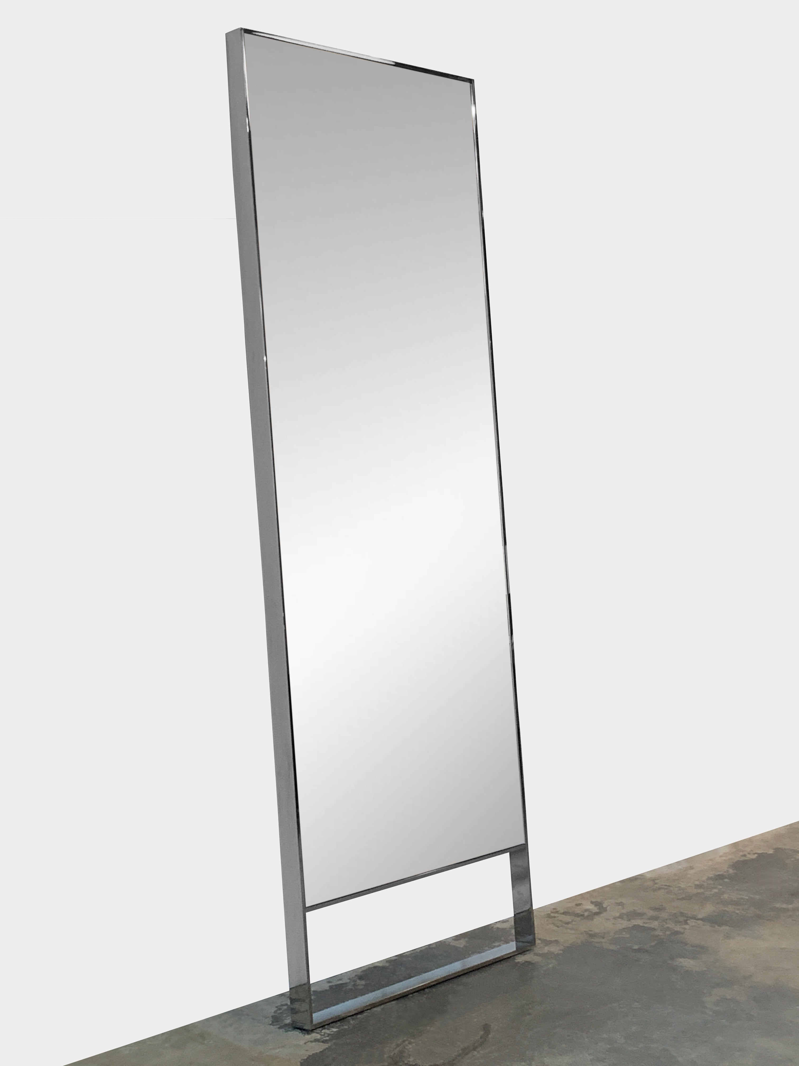 The Maxalto Psiche Mirror SMS1 Chrome, featuring a slim metallic frame, stands upright against a plain light gray background, reflecting the signature elegance of the Maxalto brand.
