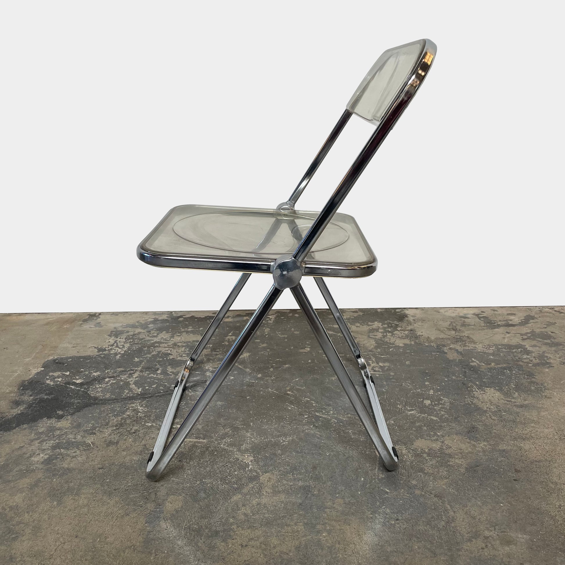 The Anonima Castelli Plia Folding Chair by Castelli, highlighted against a plain white background, echoes the iconic design of Giancarlo Piretti's Plia Folding Chairs and features the innovative "3-disc pin" mechanism.