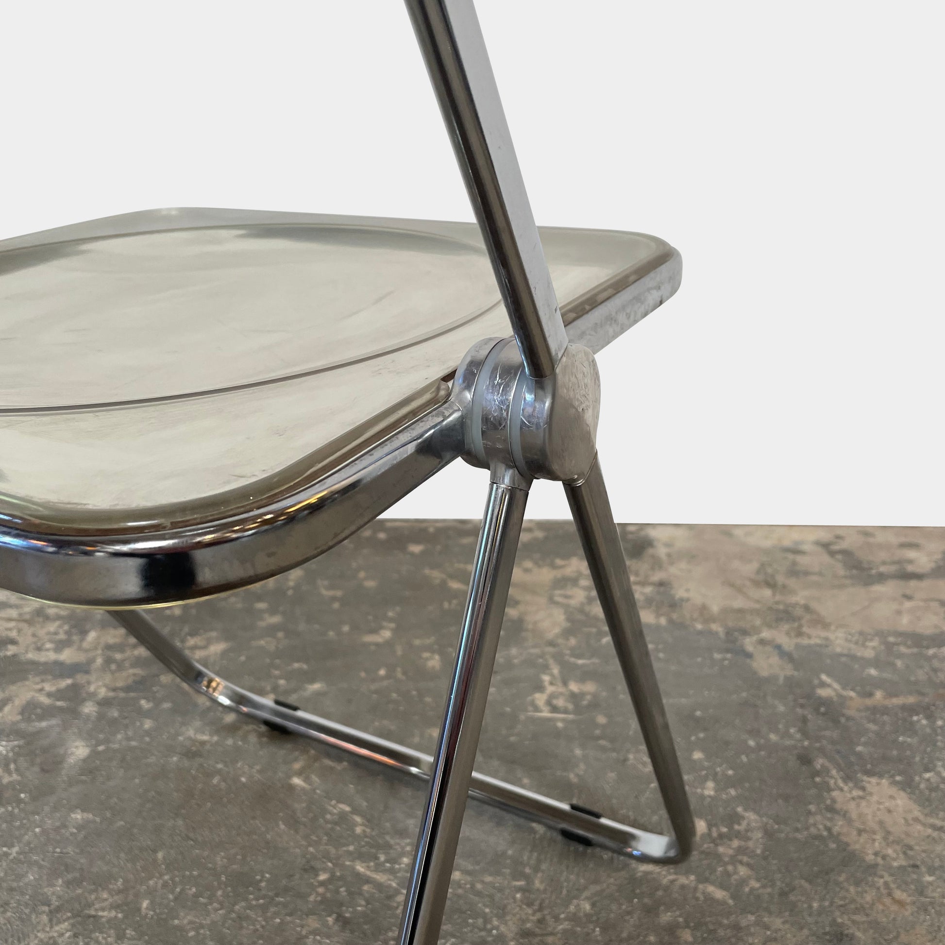 The Anonima Castelli Plia Folding Chair by Castelli, highlighted against a plain white background, echoes the iconic design of Giancarlo Piretti's Plia Folding Chairs and features the innovative "3-disc pin" mechanism.