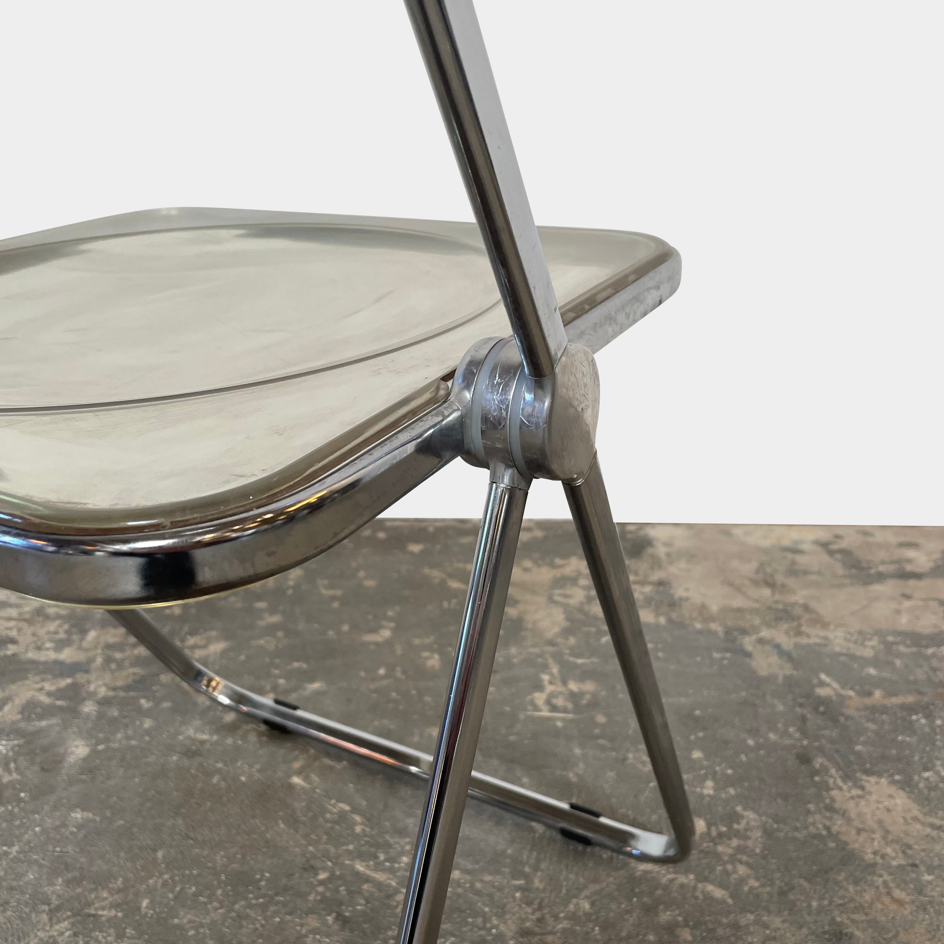 The Anonima Castelli Plia Folding Chair by Castelli, highlighted against a plain white background, echoes the iconic design of Giancarlo Piretti's Plia Folding Chairs and features the innovative "3-disc pin" mechanism.