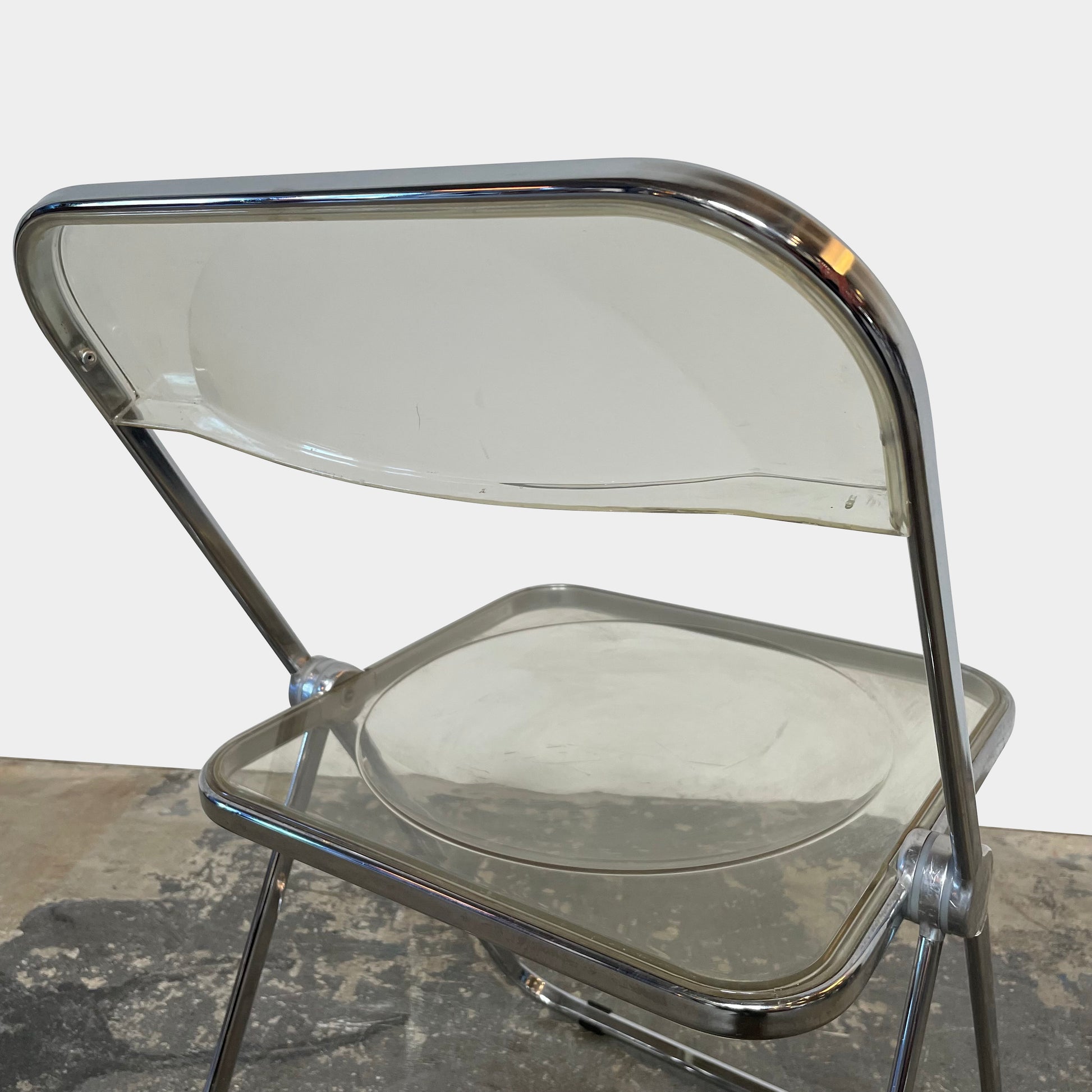 The Anonima Castelli Plia Folding Chair by Castelli, highlighted against a plain white background, echoes the iconic design of Giancarlo Piretti's Plia Folding Chairs and features the innovative "3-disc pin" mechanism.