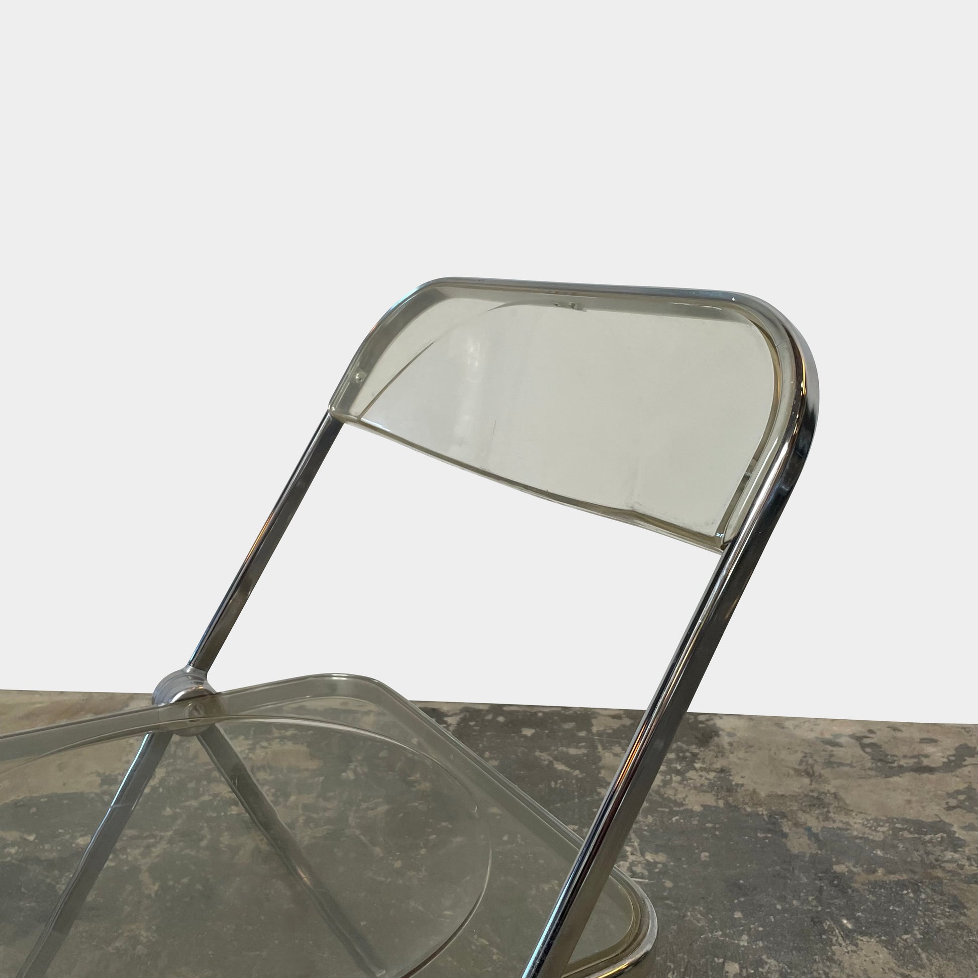 The Anonima Castelli Plia Folding Chair by Castelli, highlighted against a plain white background, echoes the iconic design of Giancarlo Piretti's Plia Folding Chairs and features the innovative "3-disc pin" mechanism.