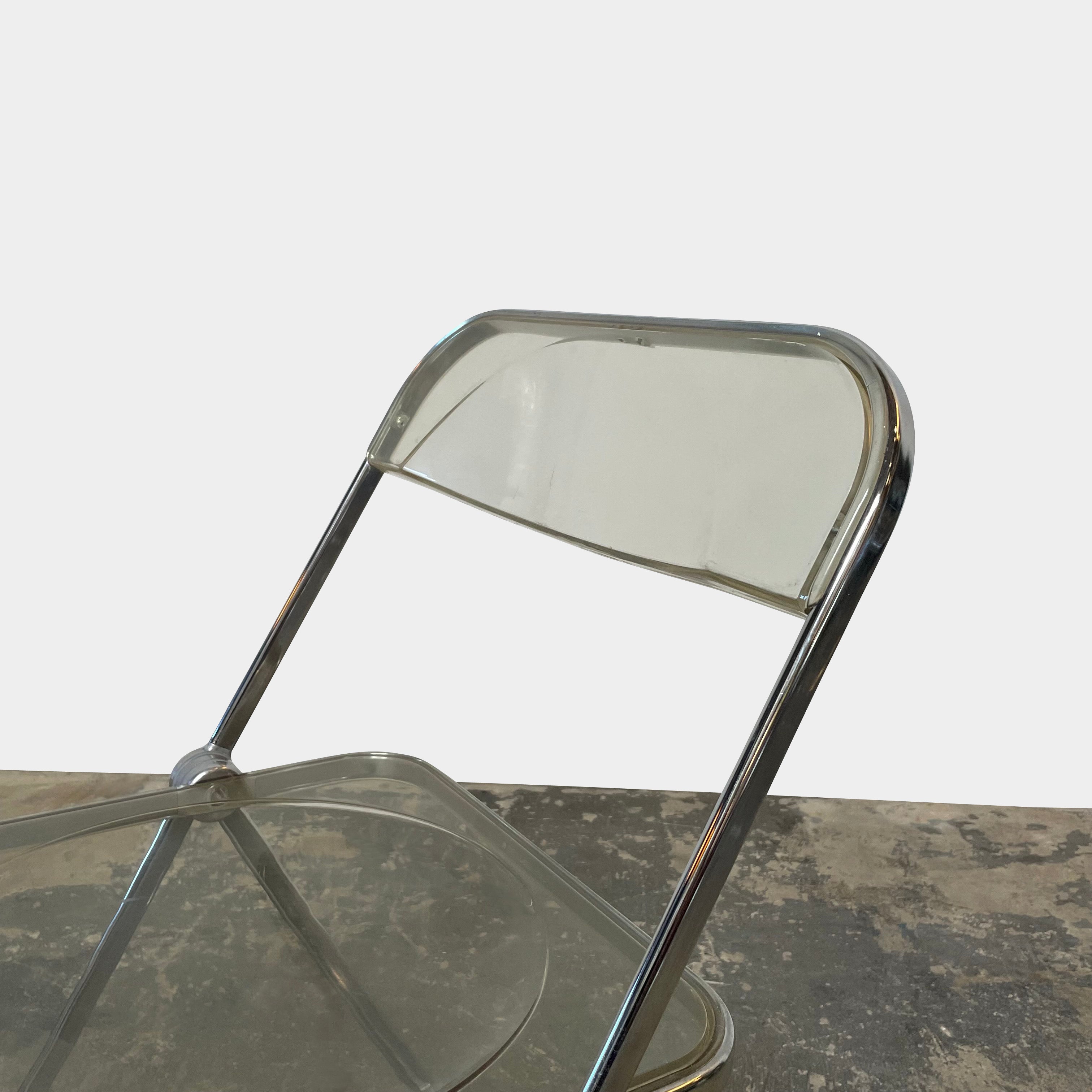 The Anonima Castelli Plia Folding Chair by Castelli, highlighted against a plain white background, echoes the iconic design of Giancarlo Piretti's Plia Folding Chairs and features the innovative "3-disc pin" mechanism.