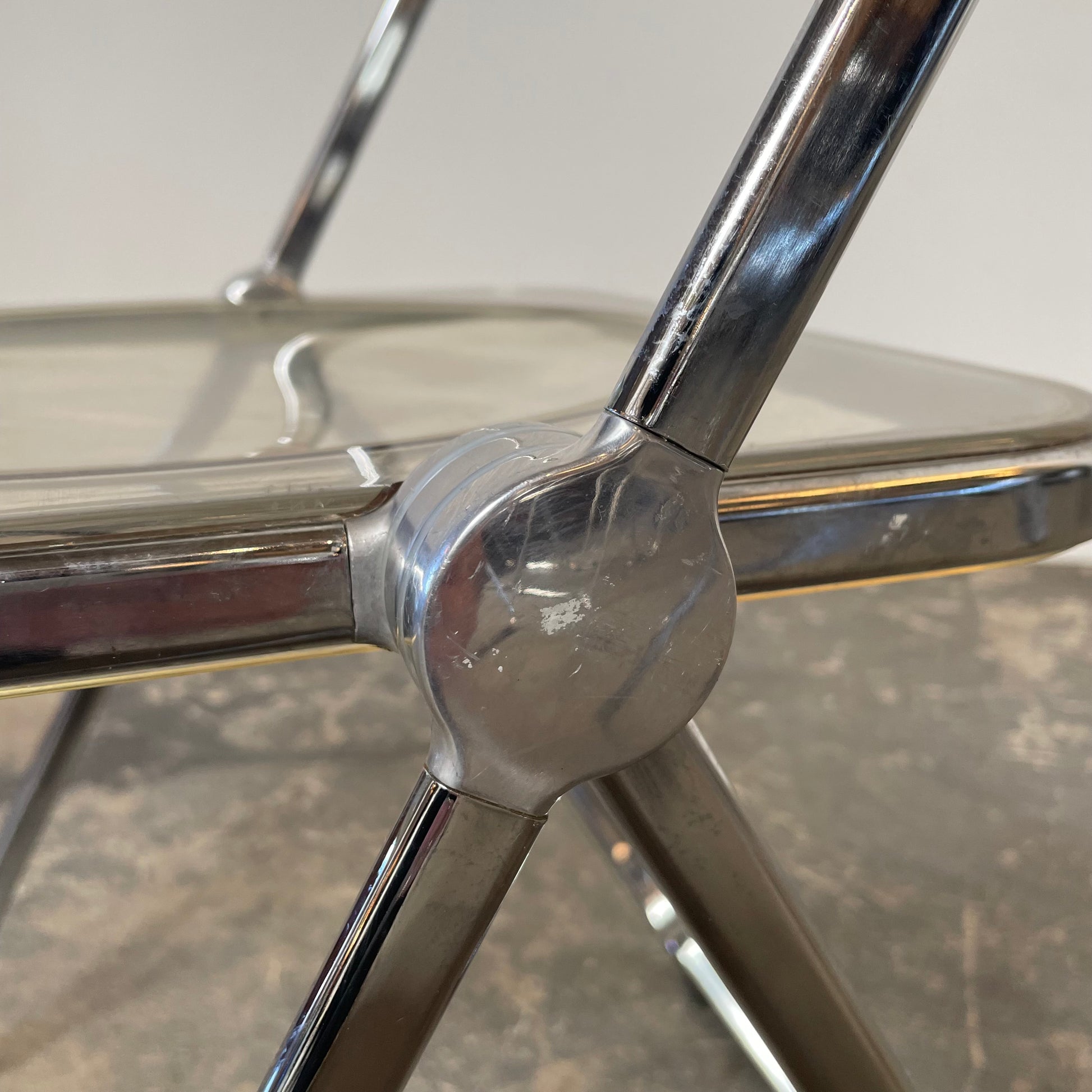 The Anonima Castelli Plia Folding Chair by Castelli, highlighted against a plain white background, echoes the iconic design of Giancarlo Piretti's Plia Folding Chairs and features the innovative "3-disc pin" mechanism.